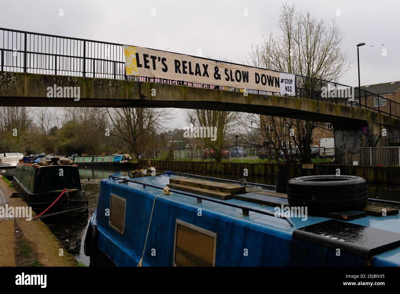 HACKNEY, LONDON - 22nd. FEBRUAR 2021: Ein Spruchband mit der Aufschrift "Lass uns entspannen und langsamer werden, Halt HS2" entlang einer Fußgängerbrücke über den Fluss lea in der Nähe von Hackney Marshes Stockfoto