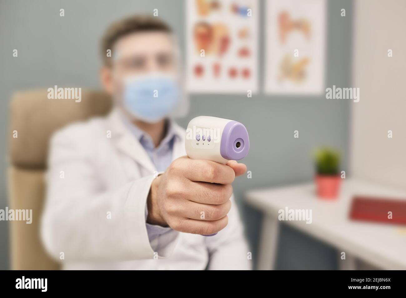 Nahaufnahme des Hausarztes mit Infrarot-Thermometer misst Körper Temperatur während eines pandemischen Coronavirus Stockfoto