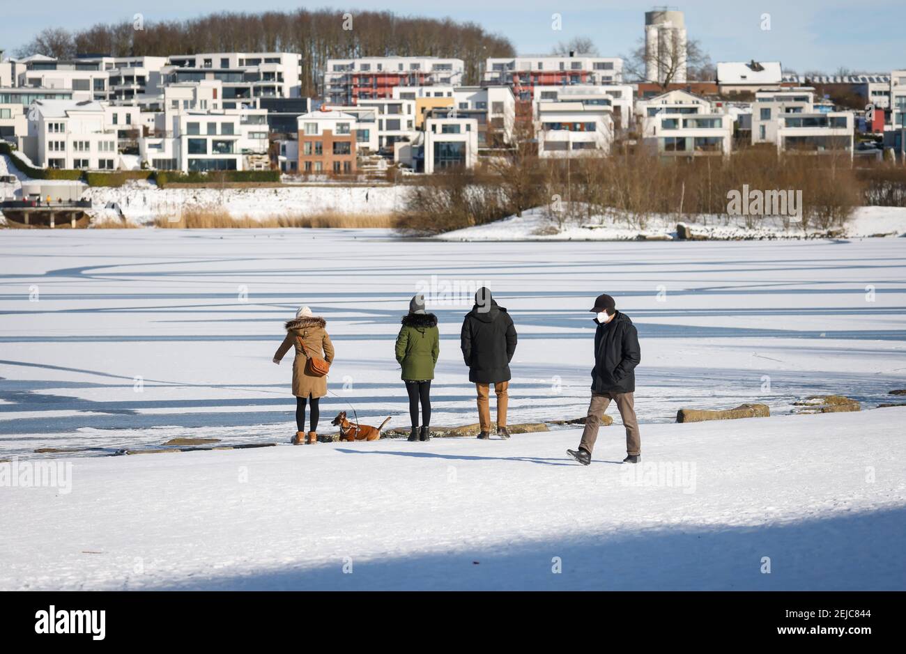 Dortmund, Ruhrgebiet, Nordrhein-Westfalen, Deutschland - Spaziergänger am Phoenix See im Winter in Eis und Schnee in Zeiten der Corona Pandemie mit Maske, hinten Stockfoto