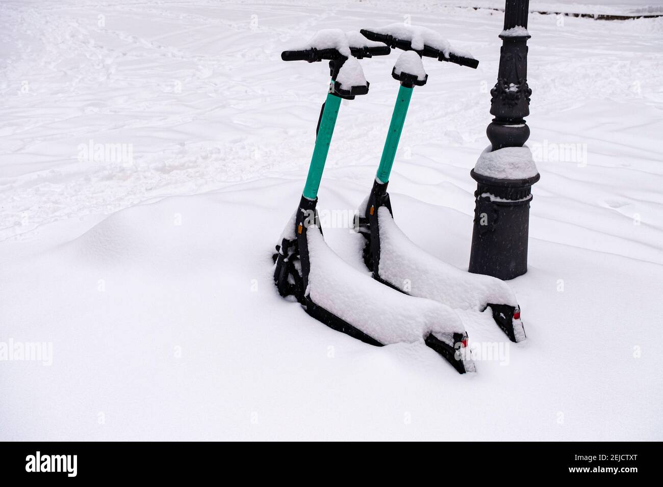 Zwei Elektro-Scooter im Winter geparkt, mit Schnee bedeckt. Stockfoto