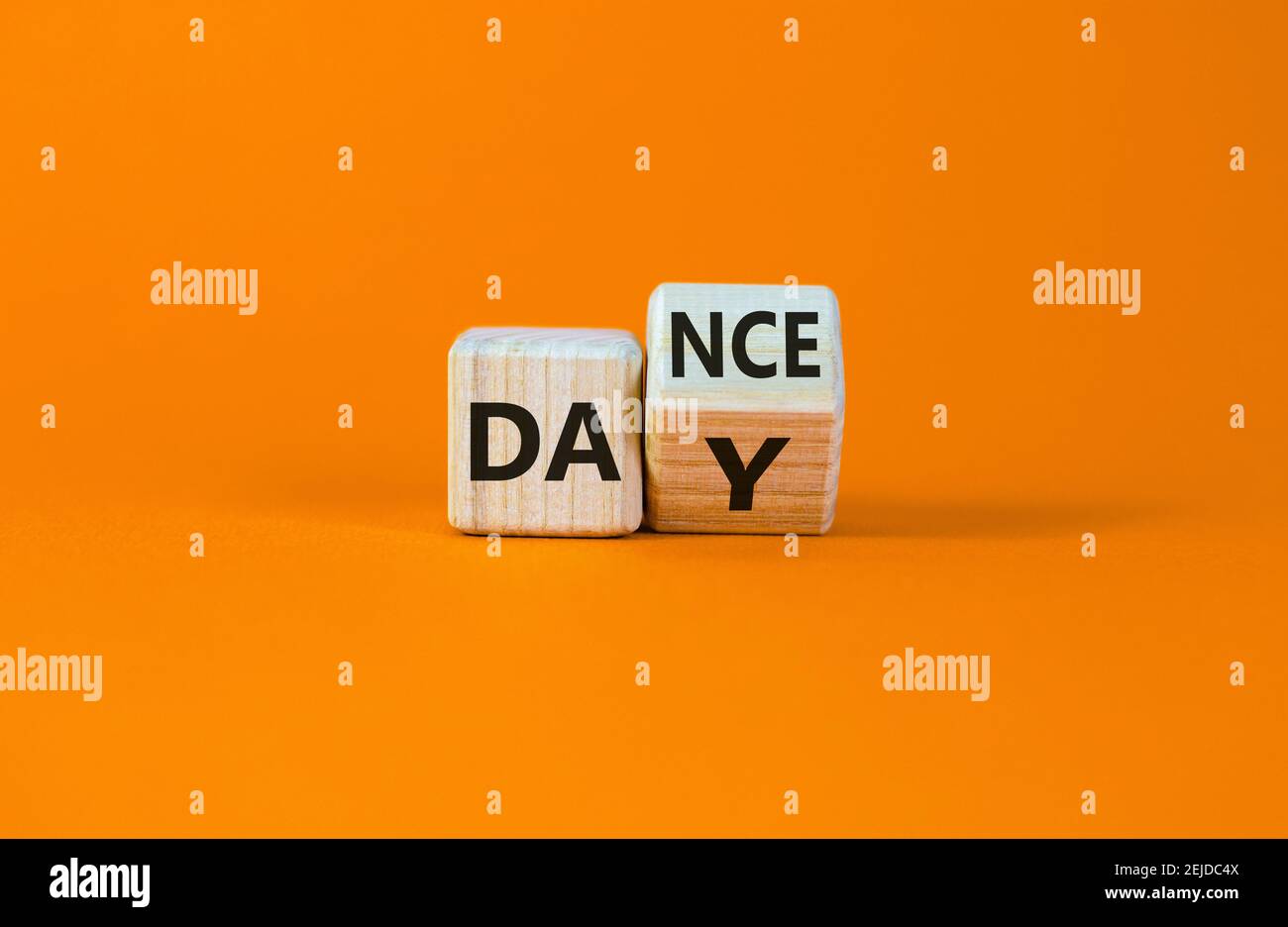 Symbol für den Internationalen Tanztag. Drehte den Würfel mit den Worten 'Tanztag'. Schöner orangefarbener Tisch, orangefarbener Hintergrund, Kopierbereich. Internationaler Tanztag Stockfoto