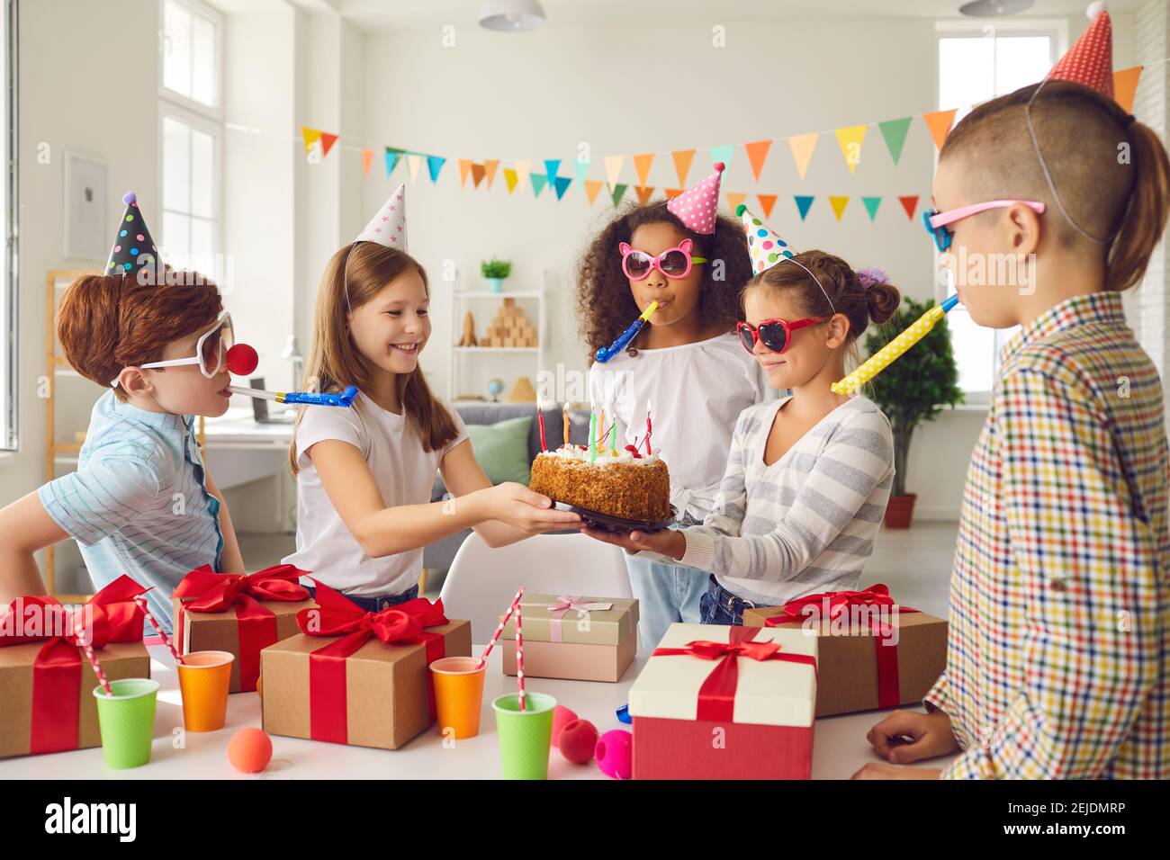 Diverse Kinder in Partyhüten und witzige Sonnenbrillen machen sich auf einer Kindergeburtstag-Party lustig. Stockfoto