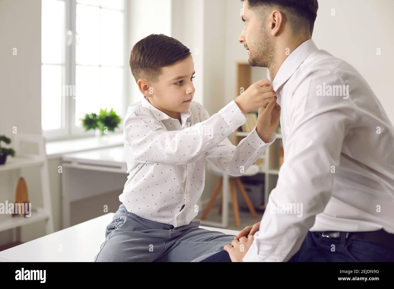 Vater und kleiner Sohn verkleiden sich und ziehen sich weiß an Hemden für besondere familiäre Anlässe Stockfoto