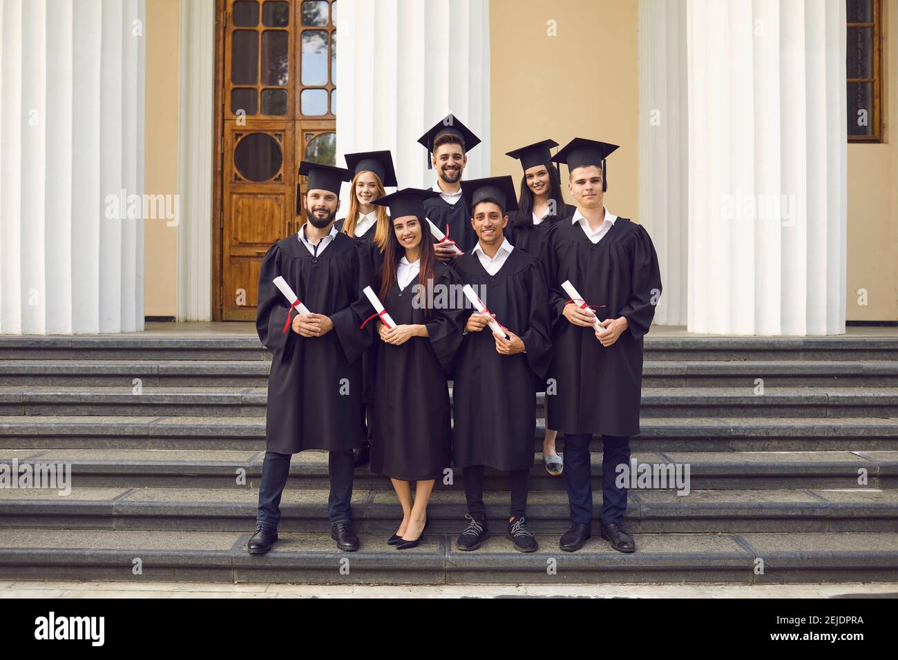 Lächelnd junge Hochschulabsolventen Klassenkameraden stehen mit Diplomen in den Händen Stockfoto