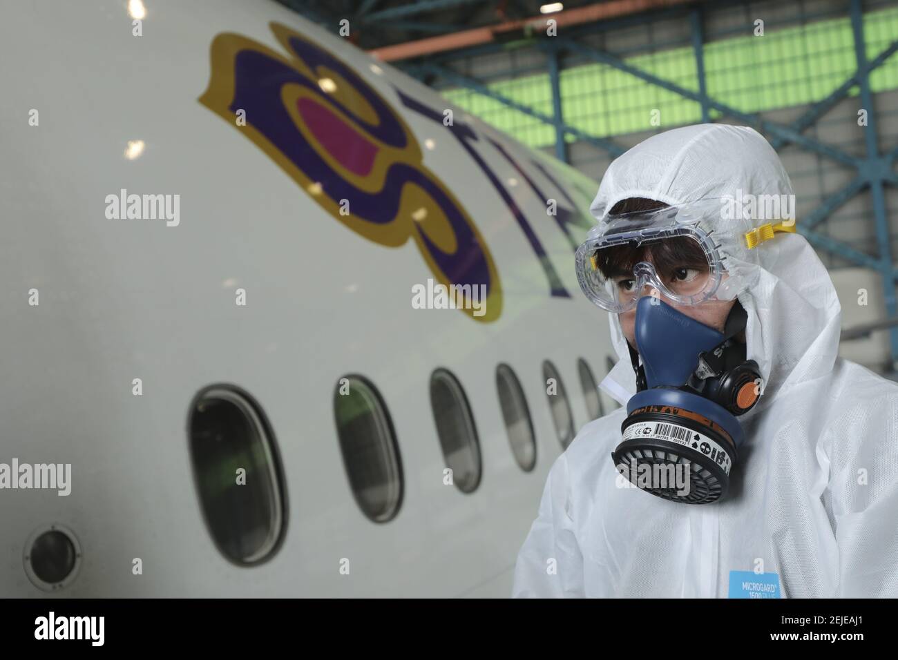 Crew-Mitglied mit Schutzanzug und Maske während des Desinfektionsvorgangs.  Thai Airways International sprüht Desinfektionsmittel auf Passagiersitzen  im Flugzeug nach einer riskanten Corona-Virus-Infektion. Thailand hat 14  Fälle entdeckt, thailändische ...