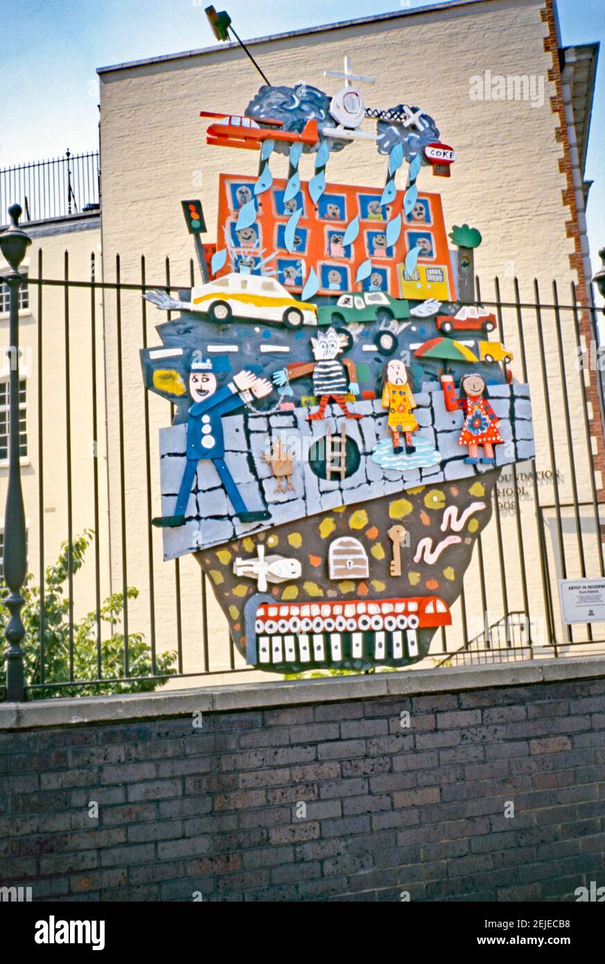 Eine farbenfrohe Reliefskulptur von Kevin Harrison aus dem Jahr 1993, die an den Geländern außerhalb der John Cass Foundation Primary School (heute Aldgate School) angebracht ist, St James's Passage, Duke's Place, London, EC3, London, England, Großbritannien 1993. Die Assemblage beinhaltete Kunst, die von den Schulkindern produziert wurde – Harrison war damals Artist in Residence an der Schule. Dies war Teil der ‘Art in the City’ von 1993 und zielte darauf ab, Skulpturen zwischen den Grünflächen und der unverwechselbaren Architektur der City of London zu setzen. Kevin Harrison (b 1953) ist ein etablierter britischer Künstler mit einem Studio im Londoner Bow. Stockfoto