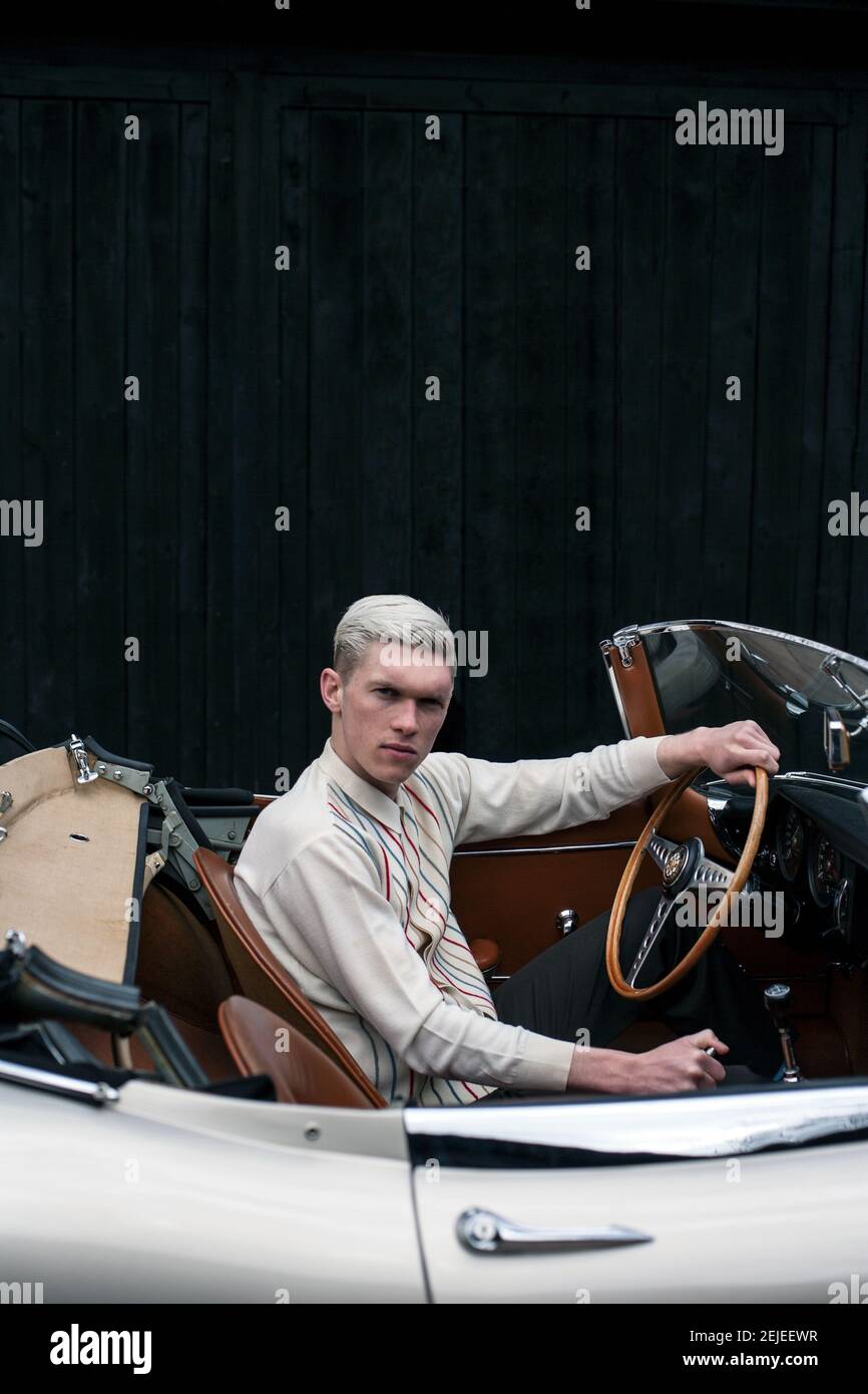 Stilvoller junger Mann auf einer Reise mit klassischen Cabriolet Blick in die Kamera, England. Stockfoto