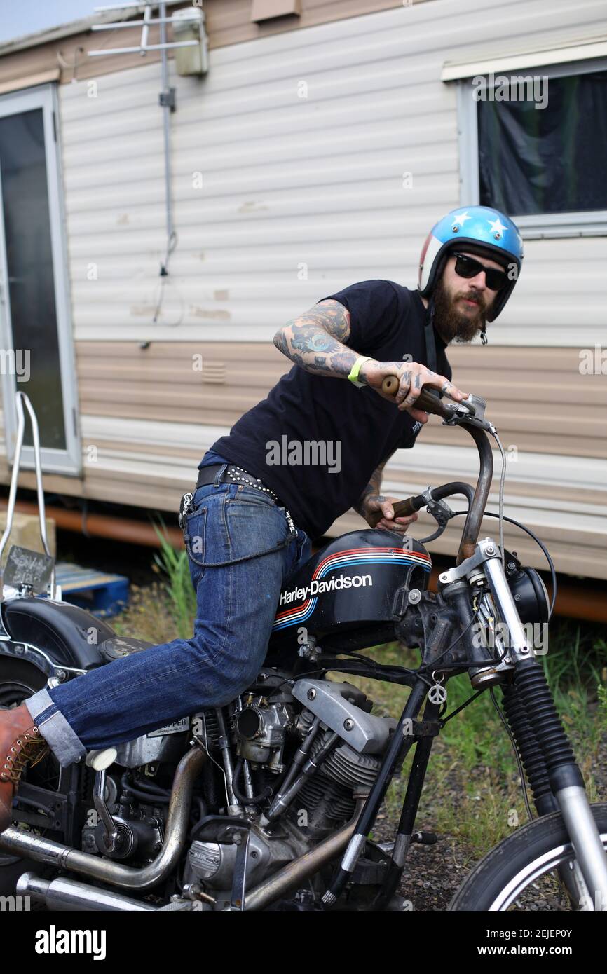 Junger Mann, der von einem Harley Davidson Motorrad mit Helm abmontiert wird Mit Sternen- und Streifenmuster Stockfoto