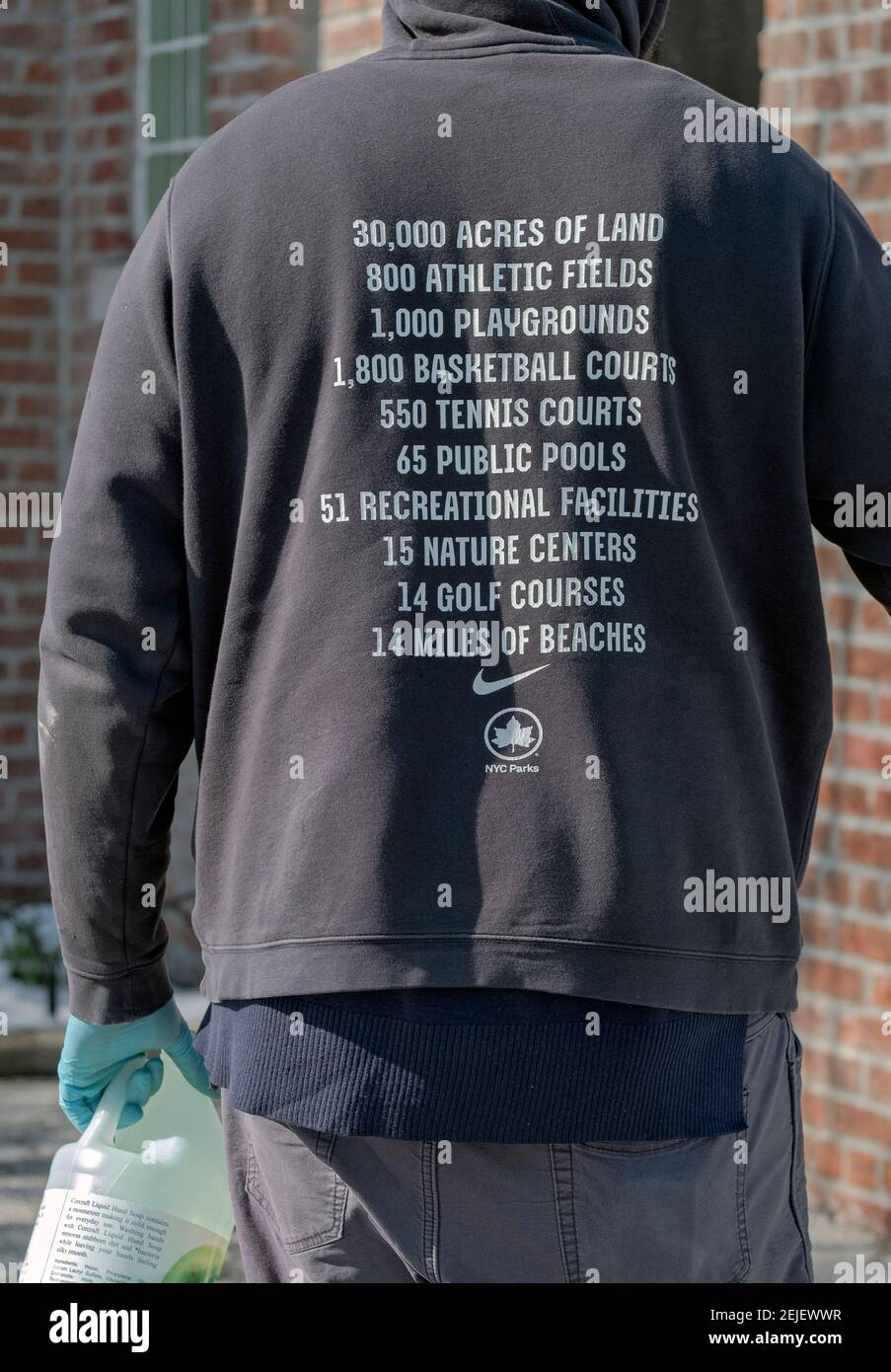 Ein anonymer Arbeiter der New Yorker Parkabteilung, der von hinten fotografiert wurde und ein Sweatshirt trägt, das die Angebote der New Yorker Parks anpreist. In Queens, NYC. Stockfoto