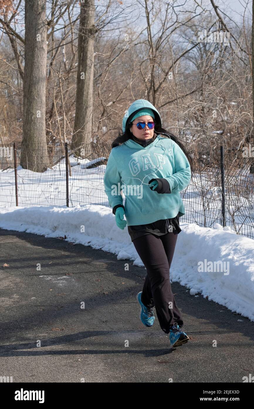 Eine farblich abgestimmte Sportlerin, die an einem kalten Wintertag in einem Park läuft. In Queens, New York City. Stockfoto