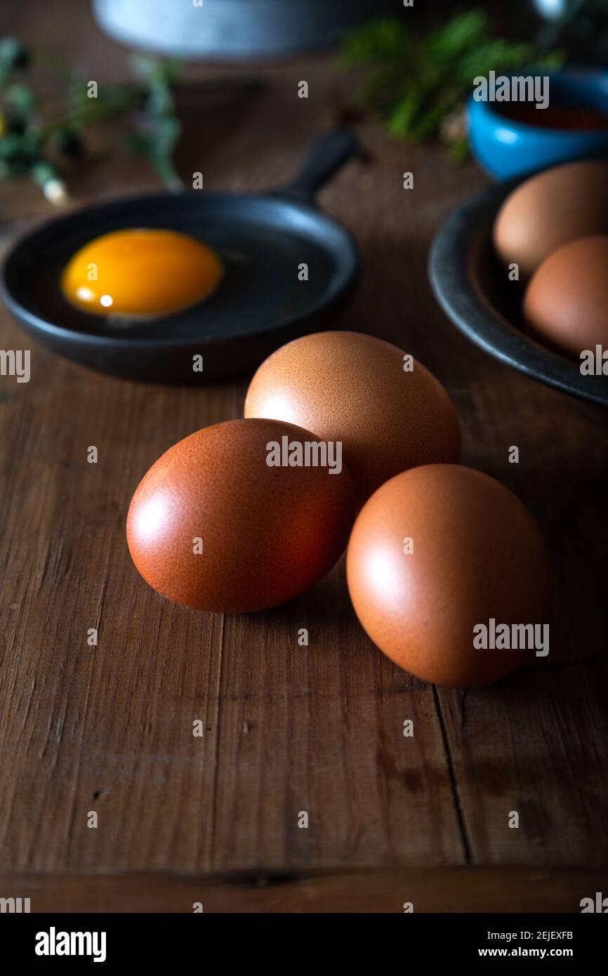 Frische ungekochte Eier in rustikaler Schüssel auf natürlichem Holzhintergrund. Rohe Hühnereier auf dem Holzhintergrund. Stockfoto