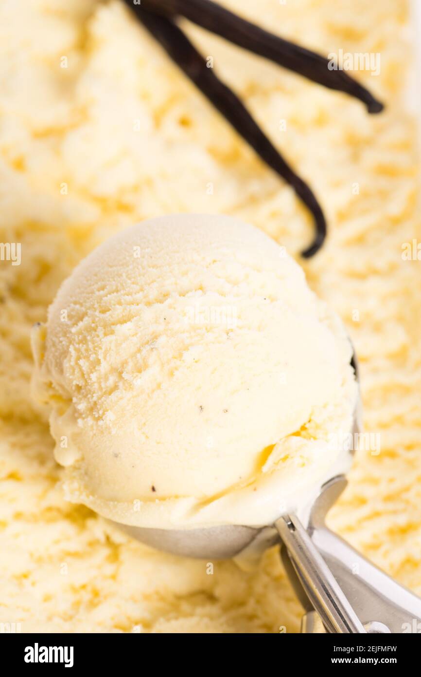Nehmen Sie Vanilleeis mit dem Eislöffel aus Die Eiscreme-Box Stockfoto