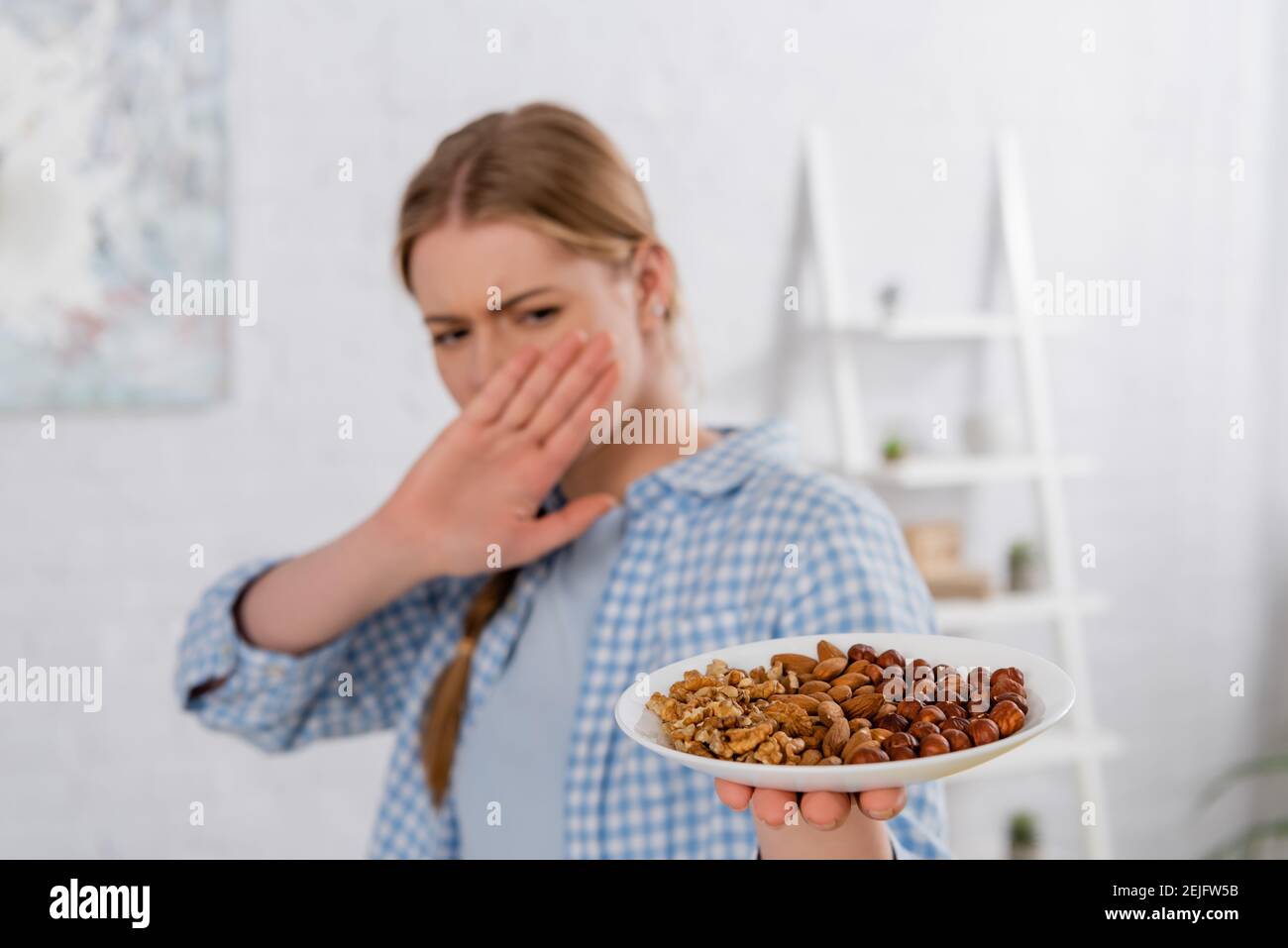 Teller mit Nüssen in der Hand der Frau mit Allergie zeigt Geste bei unscharfem Hintergrund stoppen Stockfoto