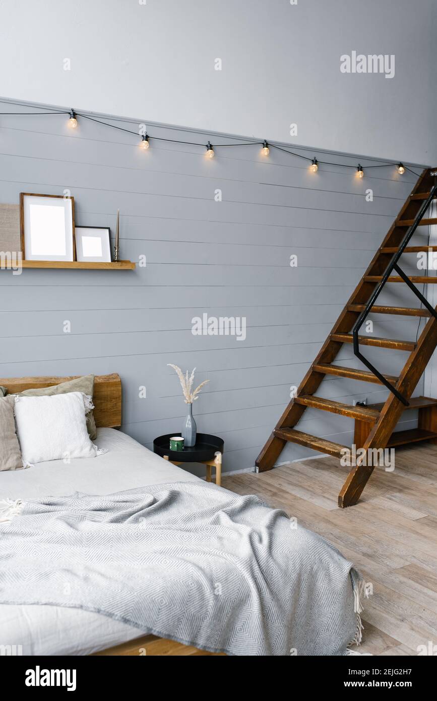 Stilvoller skandinavischer Freiraum mit Bett und Treppe zum zweiten Stock.  Designer-Zimmer mit grauen Wänden Stockfotografie - Alamy