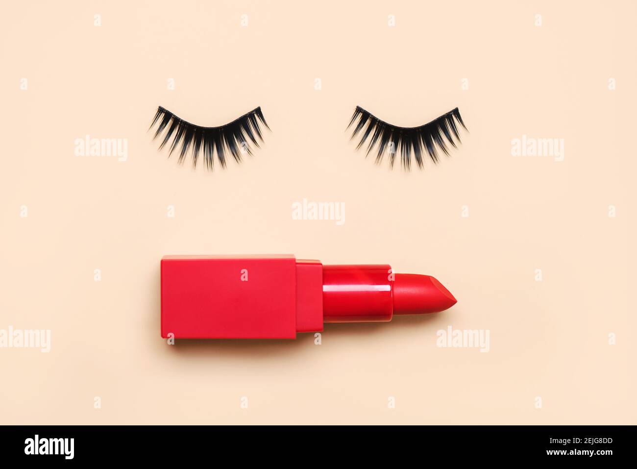 Falsche Wimpern und roter Lippenstift auf einem beigen Hintergrund.Schönheit und Make-up-Konzept Stockfoto
