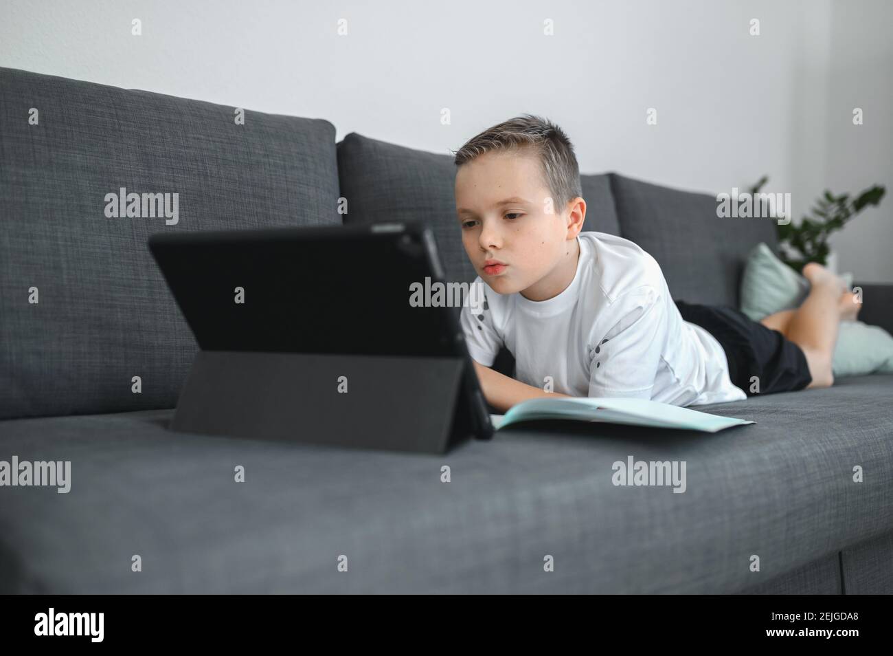 Online-Bildung, Homeschooling. Schuljunge mit Online-Unterricht zu Hause auf dem Trainer Stockfoto