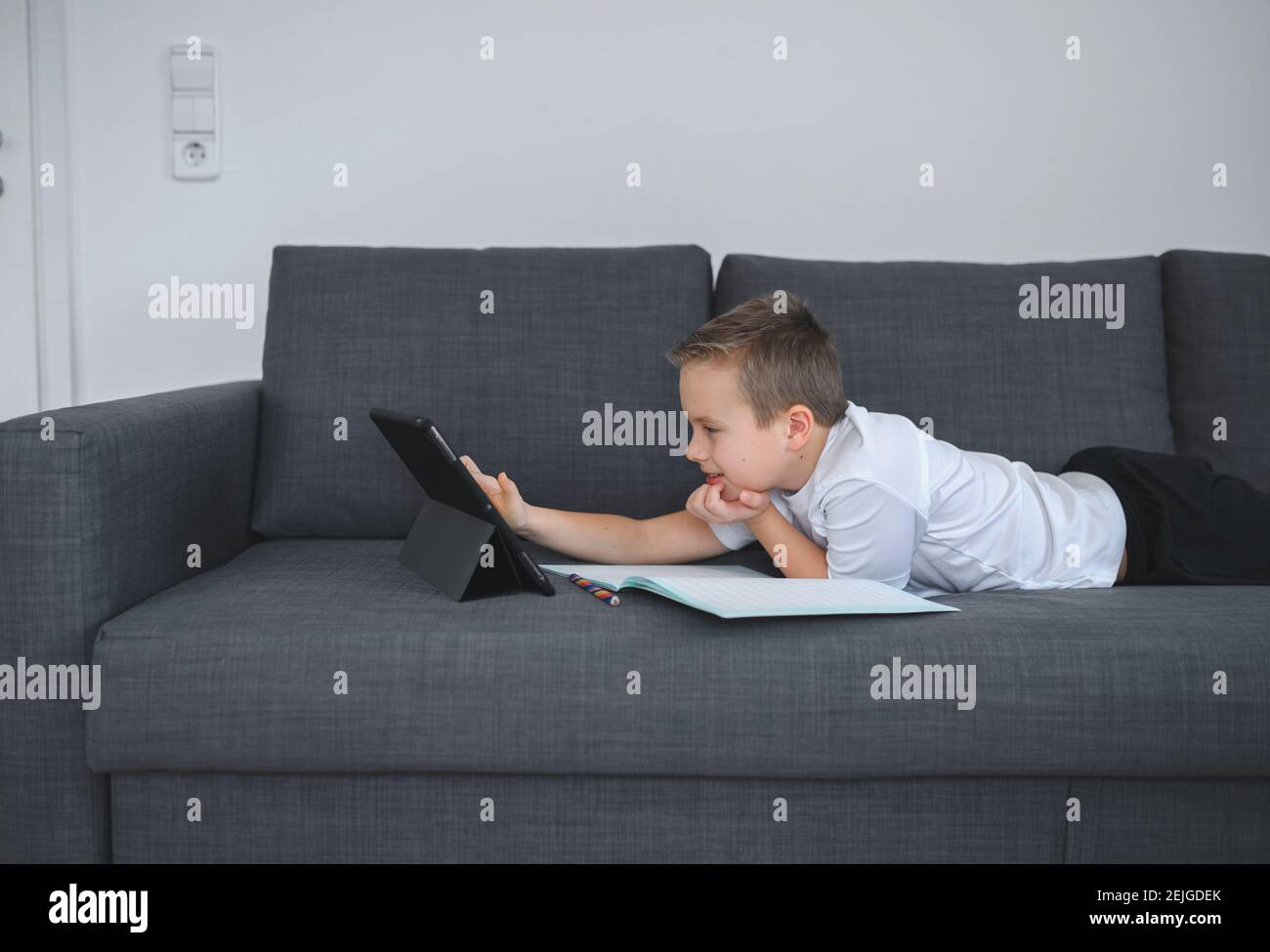 Online-Bildung, Homeschooling. Schuljunge mit Online-Unterricht zu Hause auf dem Trainer Stockfoto