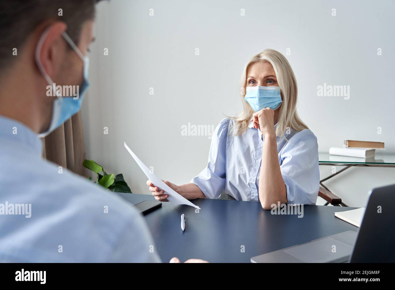 Weibliche hr-Manager trägt Gesichtsmaske hält cv bei Vorstellungsgespräch. Stockfoto