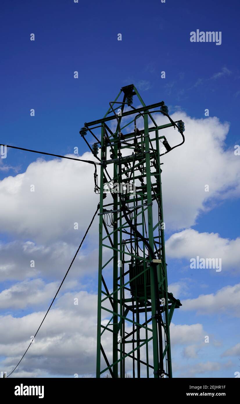 Strommast mit blauem Himmel und weißen Wolken im Hintergrund. Oberirdische Stromleitung. Stockfoto