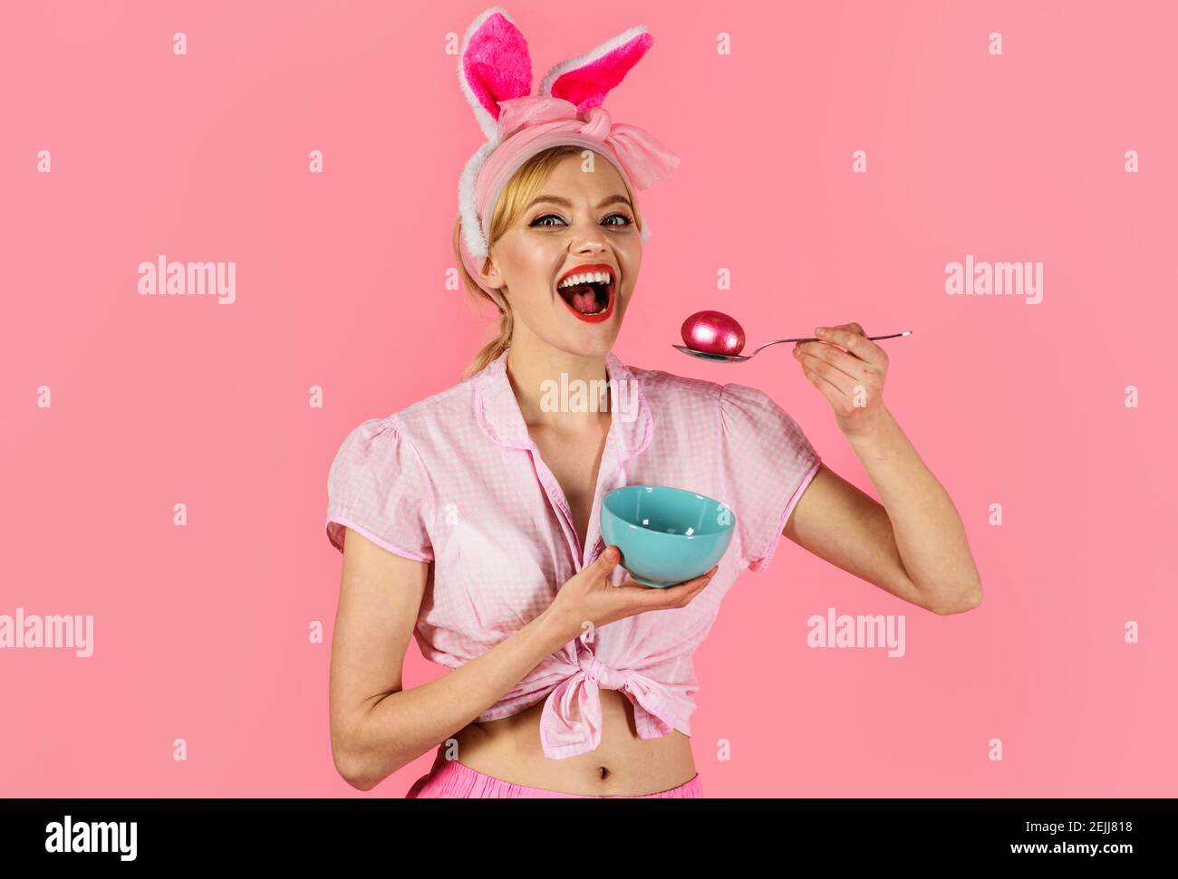 Osterfest. Frau mit gefärbtem Ei. Lächelndes Mädchen in Hasenohren. Eier jagen. Stockfoto
