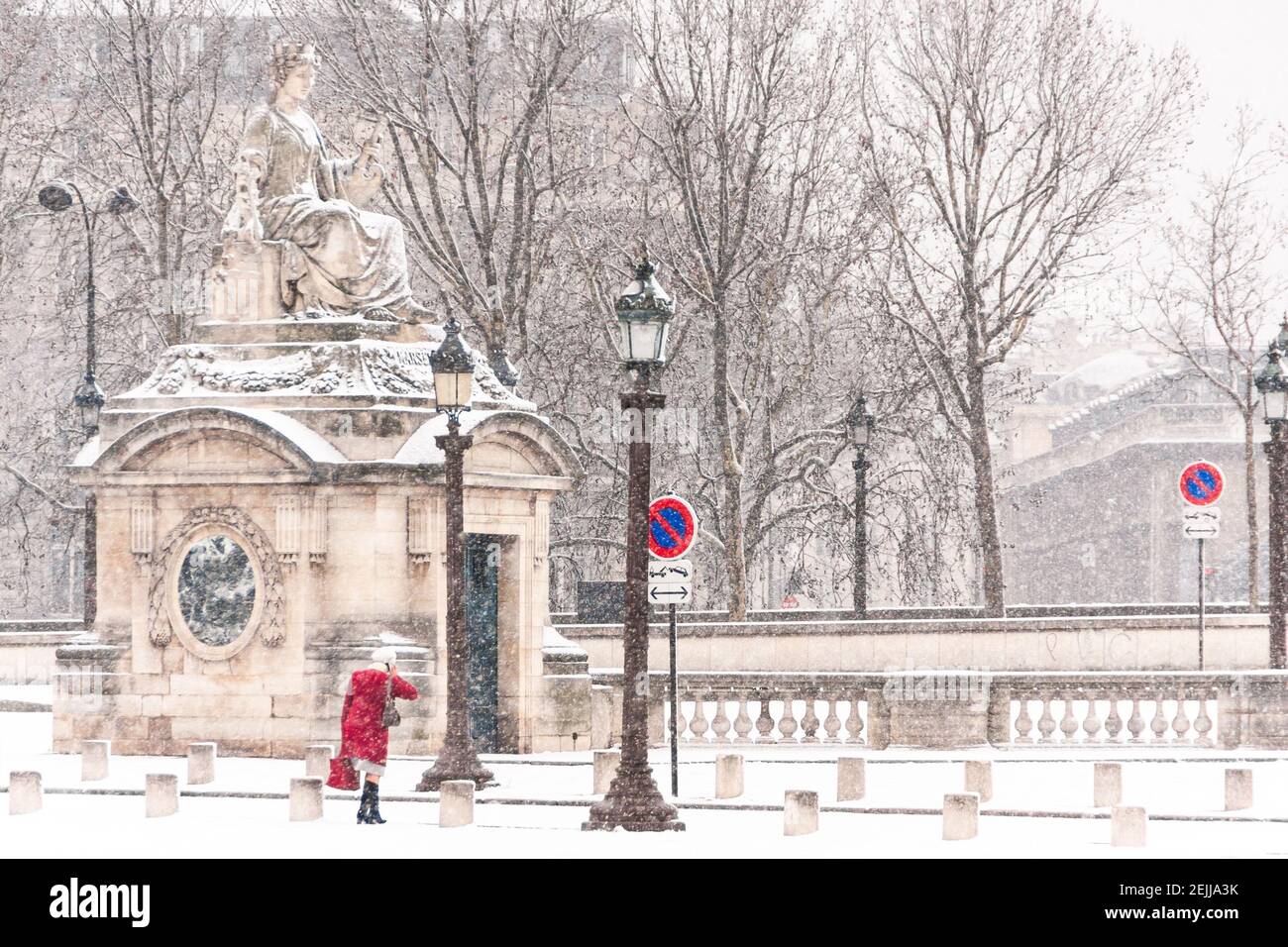Frau mit einem roten Mantel geht in Place de la Concorde in Paris im Winter beim Schneefall Stockfoto