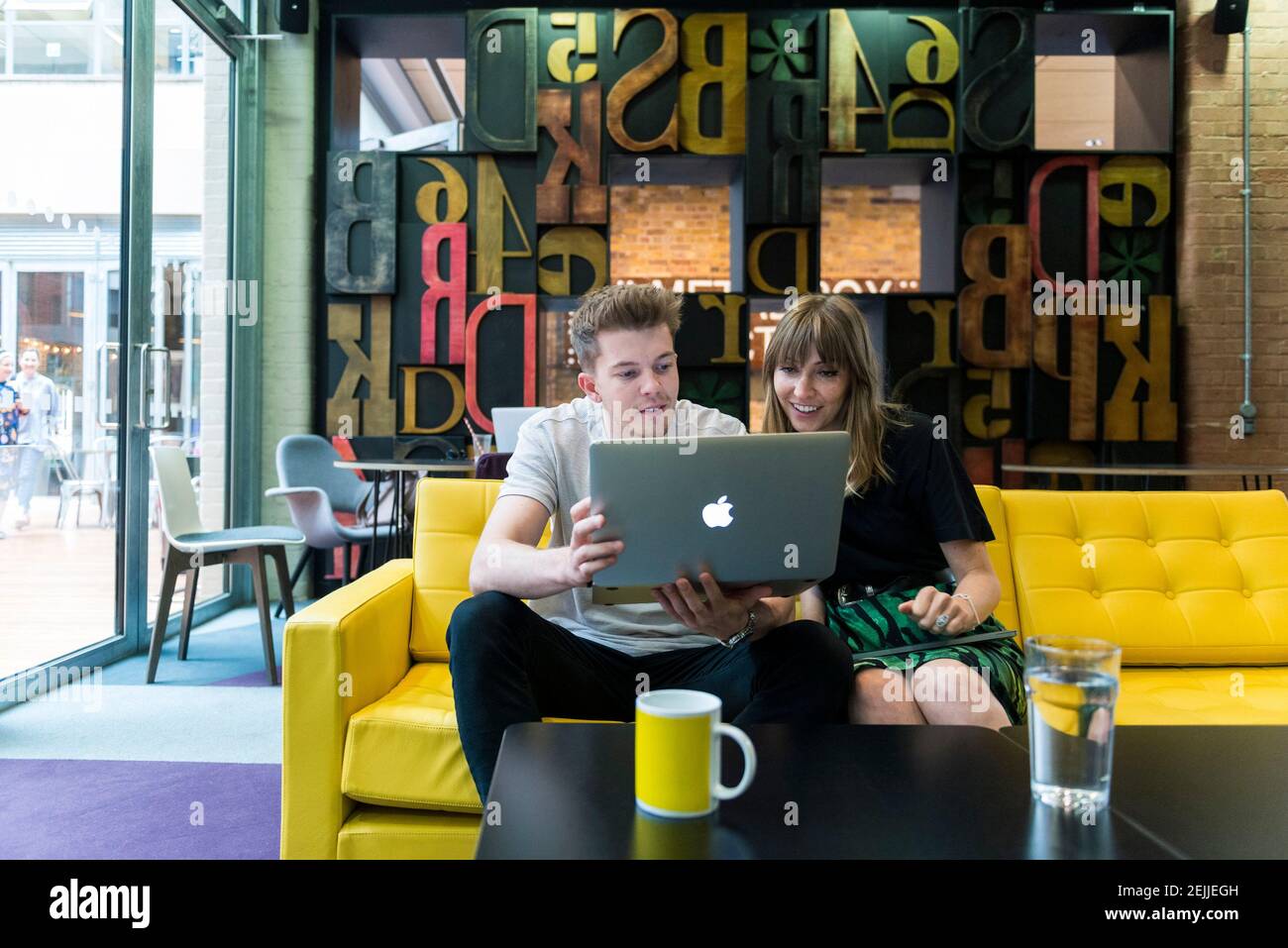 Büroangestellte sitzen auf einem Sofa und treffen sich schnell und informell mit ihren Laptops Stockfoto