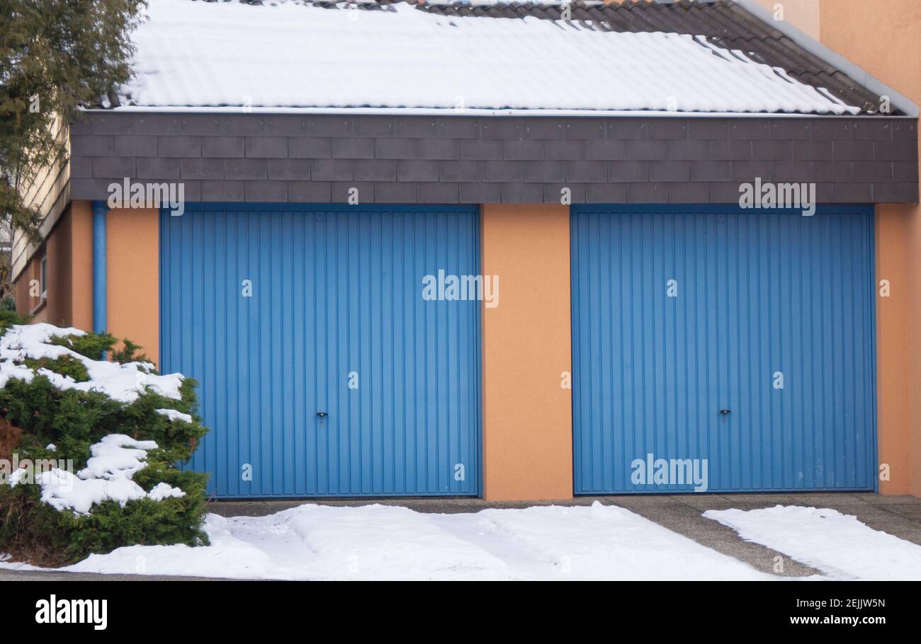 Orange Garage mit Blauen Garagentoren und Schnee auf dem Dach And in the infound Stockfoto