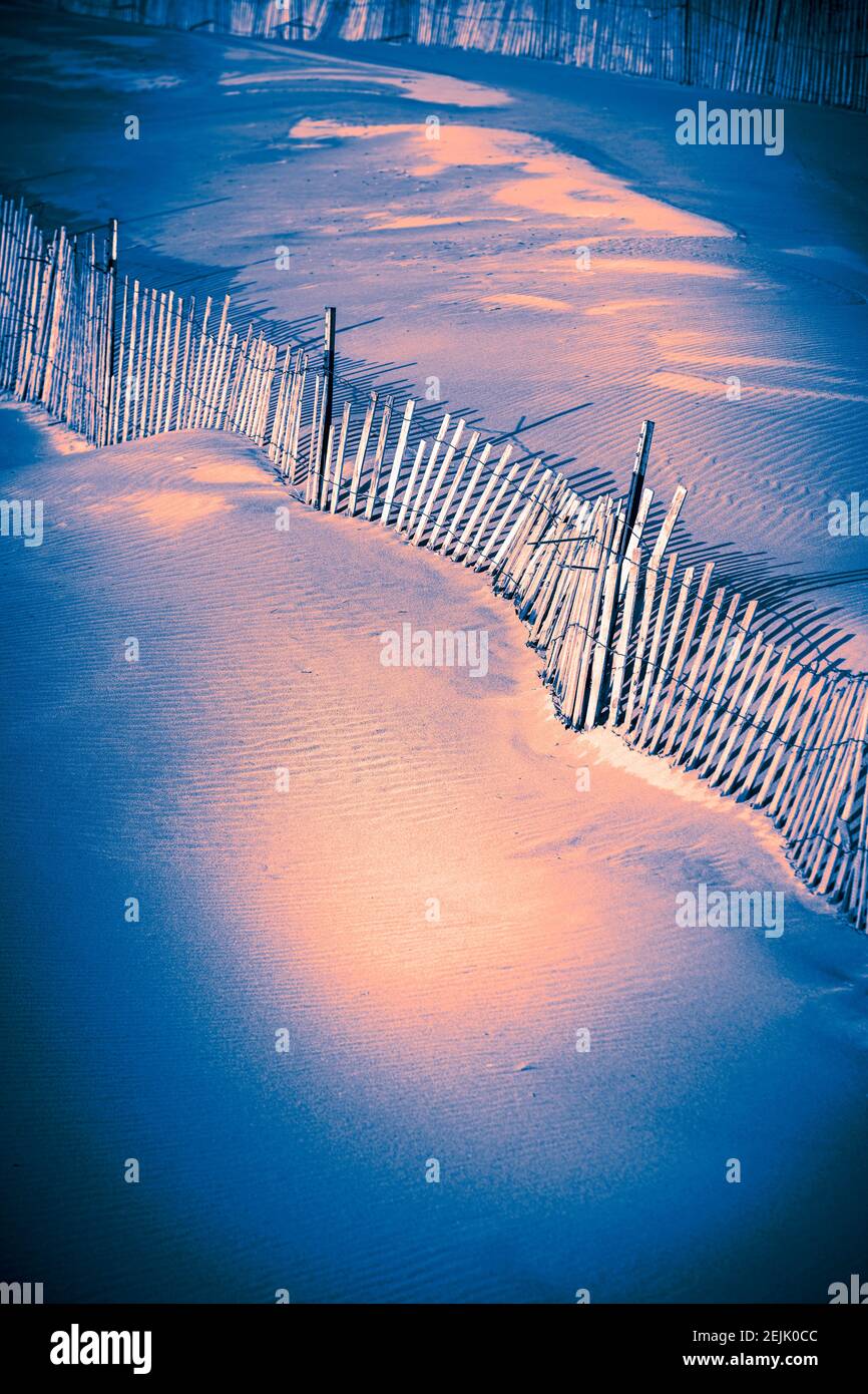 Schneezaun mit Schatten entlang windgedrifteten Sand in der Nähe des Ludington State Park Beach House am Lake Michigan in der Nähe von Ludington, Michigan, USA. Ludington S. Stockfoto