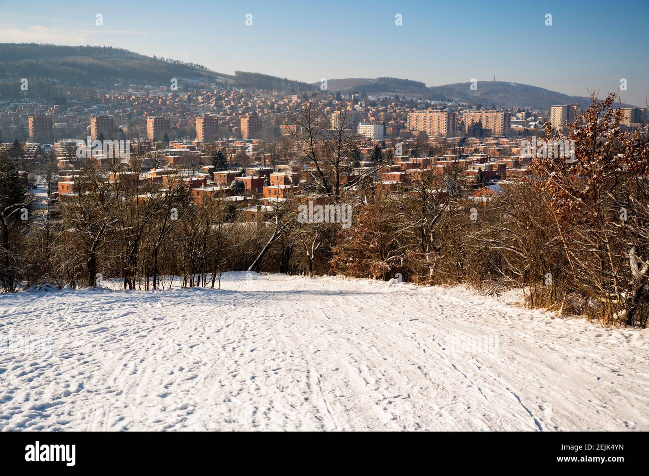 Panoramablick auf einen Teil der Stadt Zlin mit typischer Architektur aus roten Backsteinhäusern, verschneiten Hügeln und Hügeln rund um die Stadt in schneebedeckten sonnigen Wintertag. Cze Stockfoto