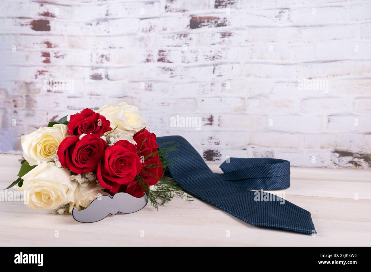 Vatertagskonzept mit Schnurrbart, weißen, roten Rosen und blauer Krawatte auf Holzhintergrund. Leerzeichen für Text. Stockfoto