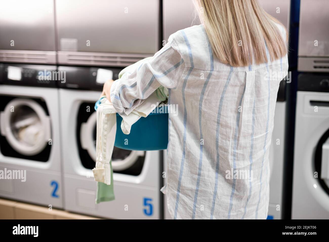 Frau, die Wäsche in der Waschküche mit Waschmaschine, hält Korb mit  Bettwäsche und Handtücher in den Händen. Moderne Technologien, Reinigung  und Waschen con Stockfotografie - Alamy