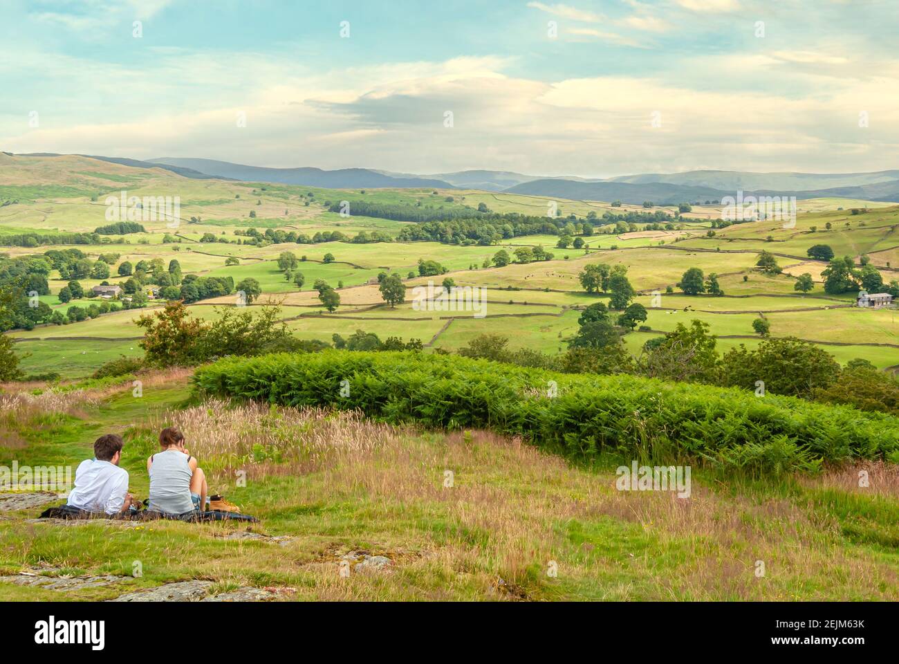 Das junge Paar genießt den Blick vom Aussichtspunkt Orrest Head in der Nähe von Windermere, Lake District, Cumbria, England, Großbritannien Stockfoto