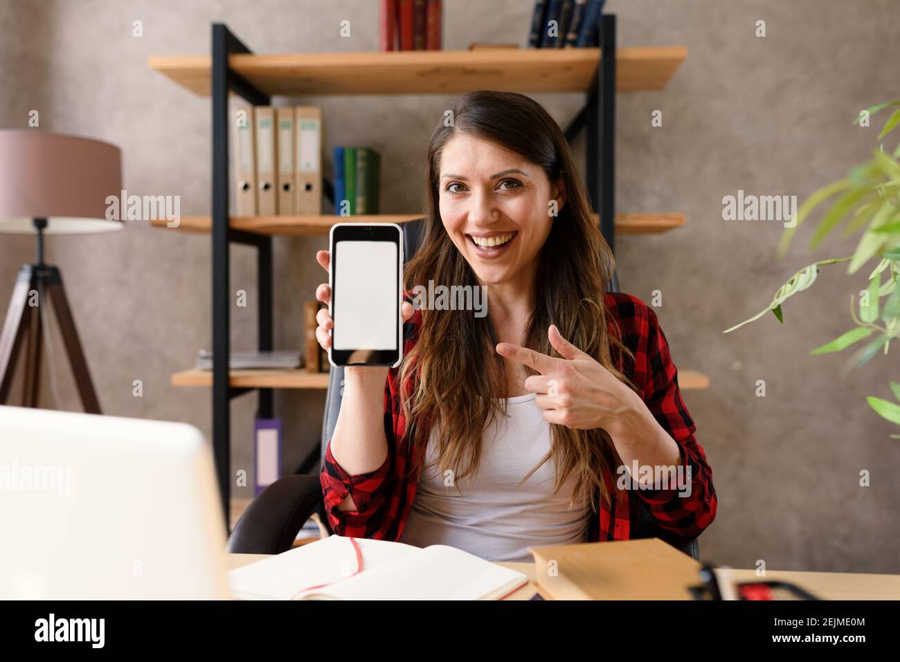 Glückliche Frau zeigt etwas in ihrem modernen Smartphone Stockfoto