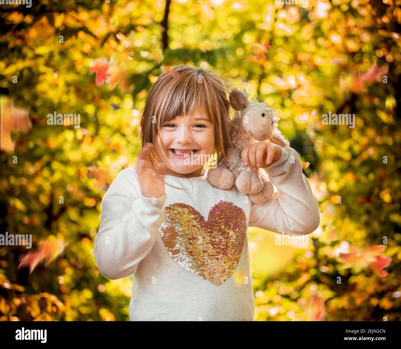 Little Happy Girl mit plüschigen Tier winken und lächeln an Ein sonniger Herbsttag im Spätsommer in einer natürlichen Wald Provincial Park während einer Familie vacatio Stockfoto