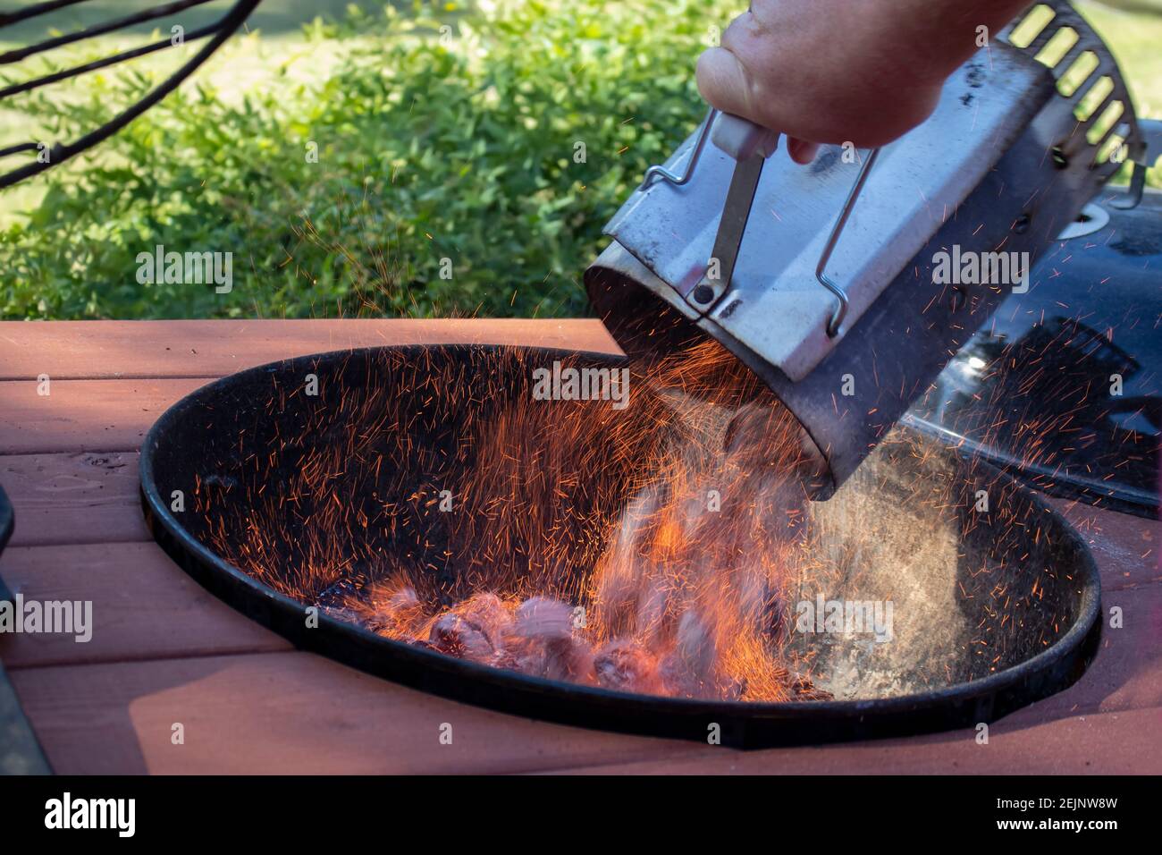 BBQ Kamin Holzkohle Feuer Starter voll von brennenden Briketts werden In einen Grill im Freien geworfen mit Funken fliegen Stockfoto