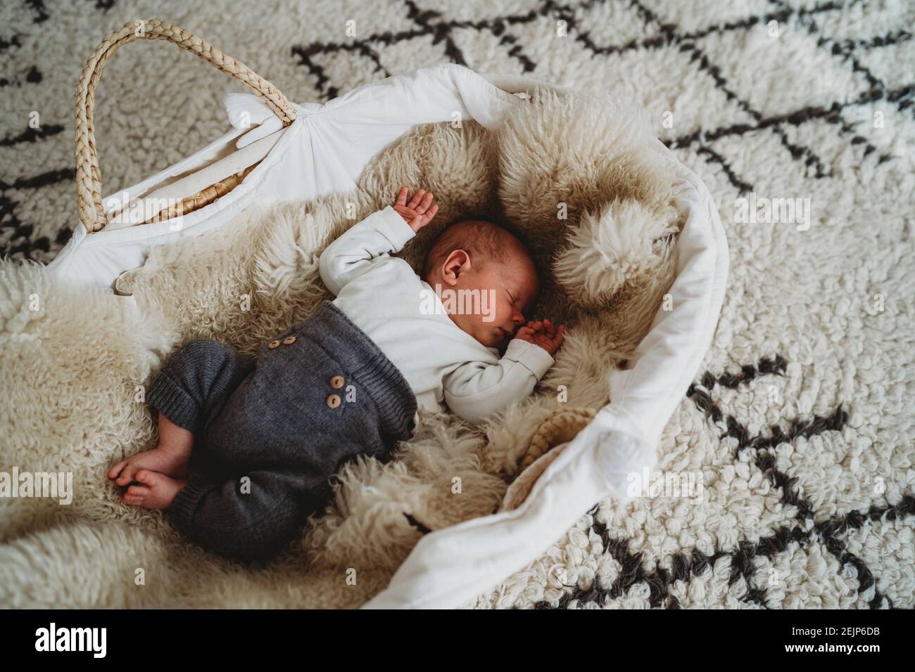 Liebenswert weiß neugeborenes Baby schlafen in Moses Korb mit gemütlich Teppich Stockfoto