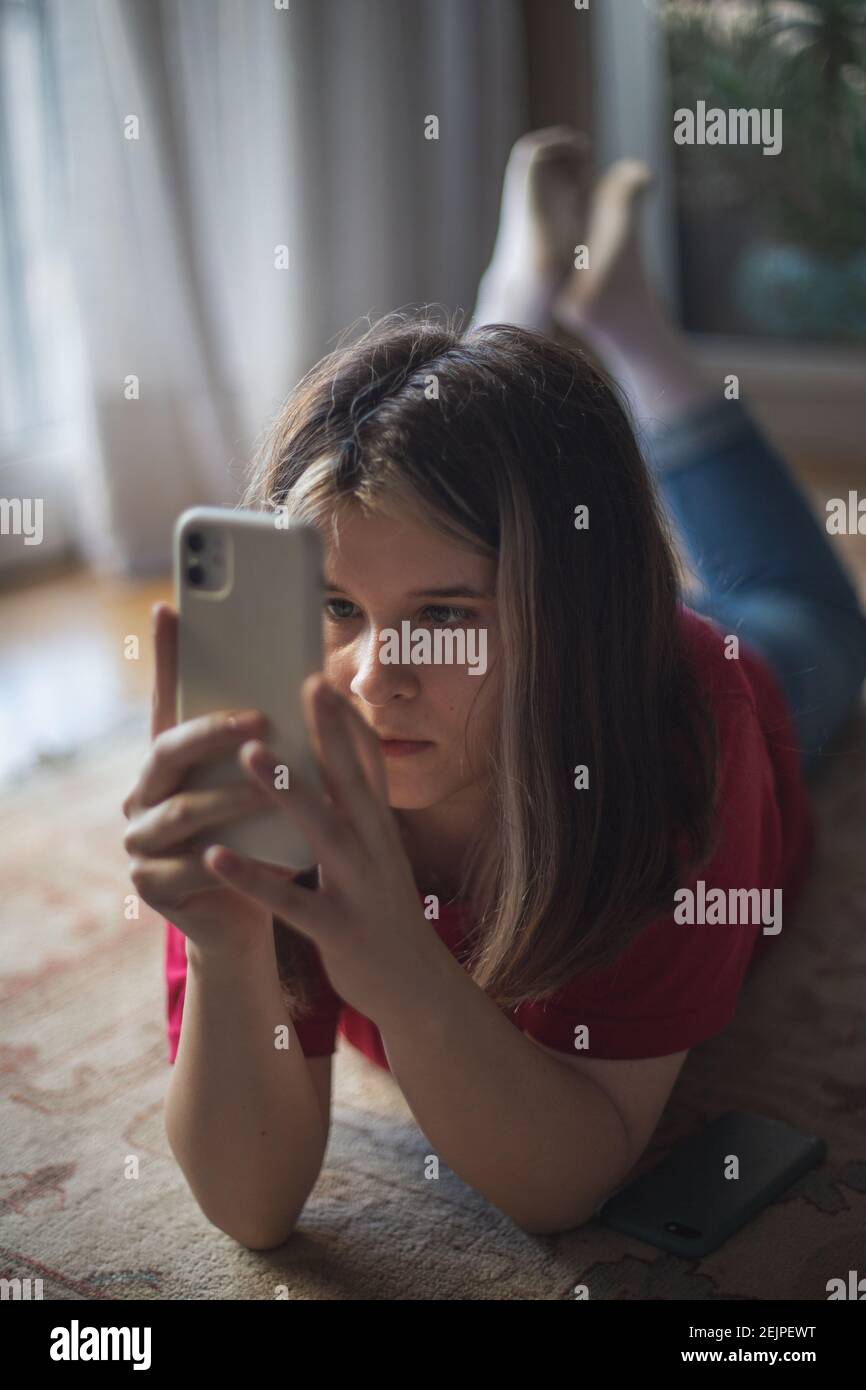 Ein Mädchen im Teenageralter schaut auf den Bildschirm ihres Smartphones Stockfoto