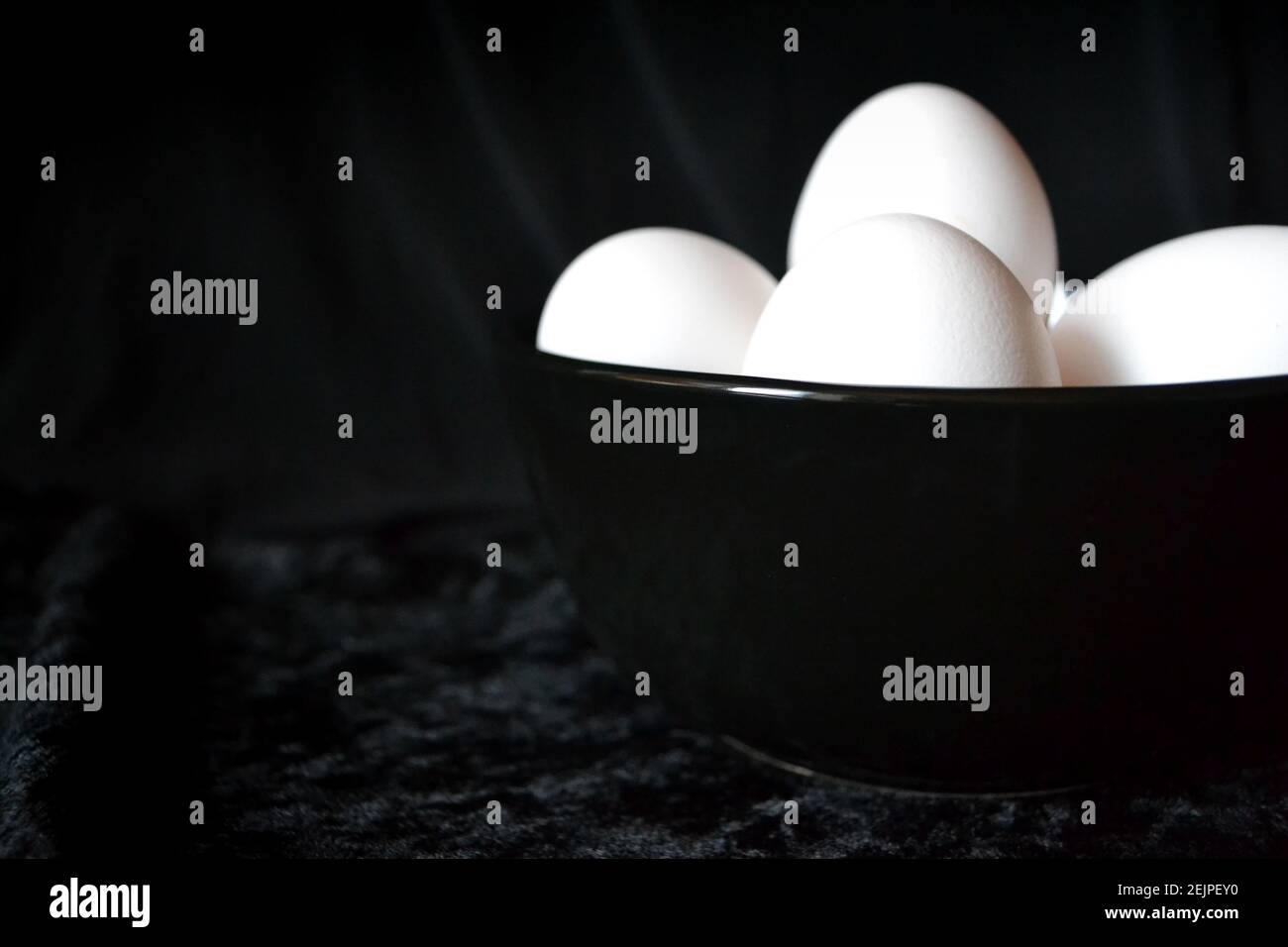 Weiße Eier innen schwarze Platte vor schwarzem Hintergrund Stockfoto