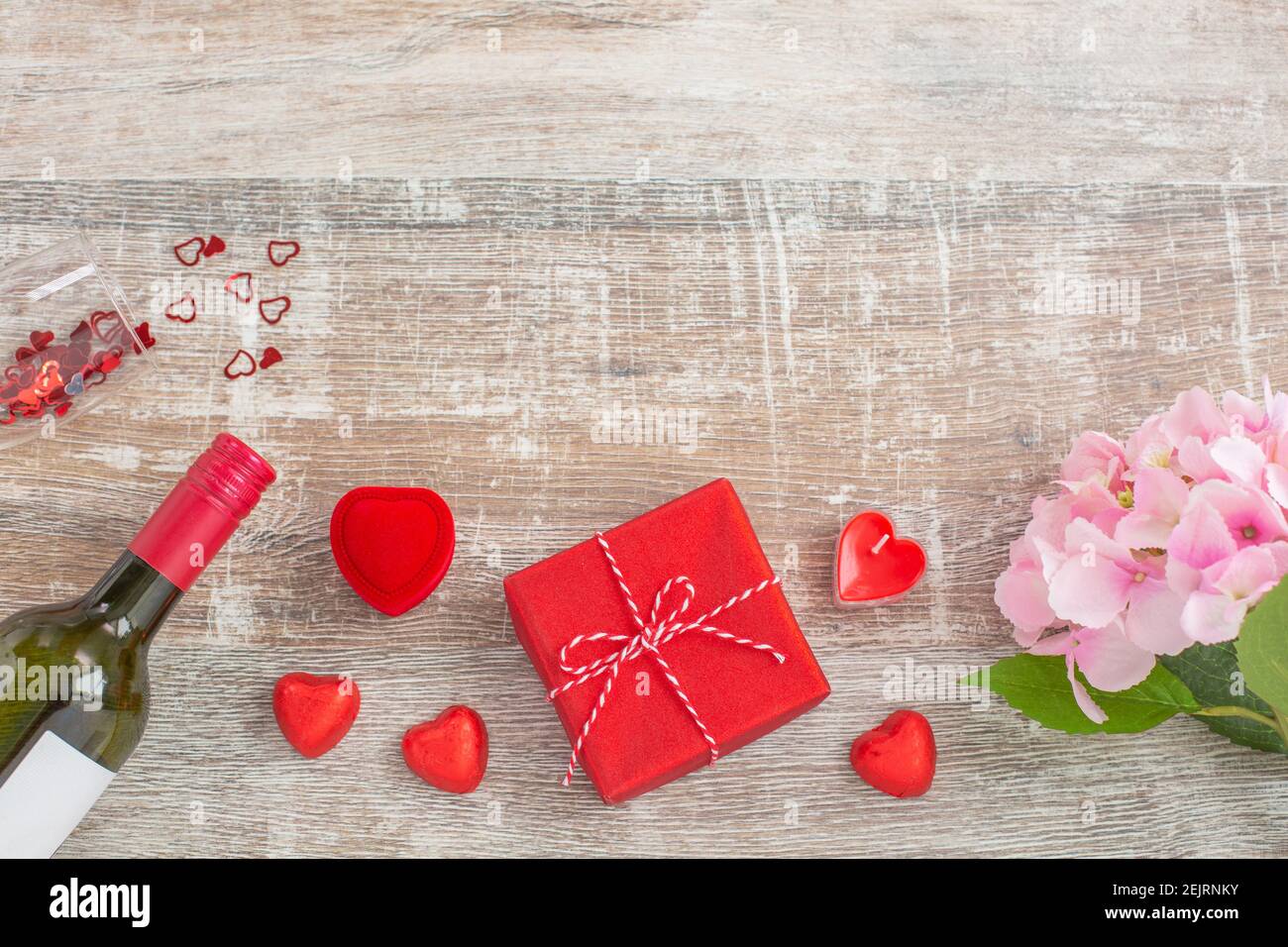 Rotwein-Flasche und Liebe Geschenk-Boxen, Kerzen, Blumen auf Holzhintergrund. Valentinstag. Das Konzept von Urlaub und Liebe. Flach liegend Stockfoto
