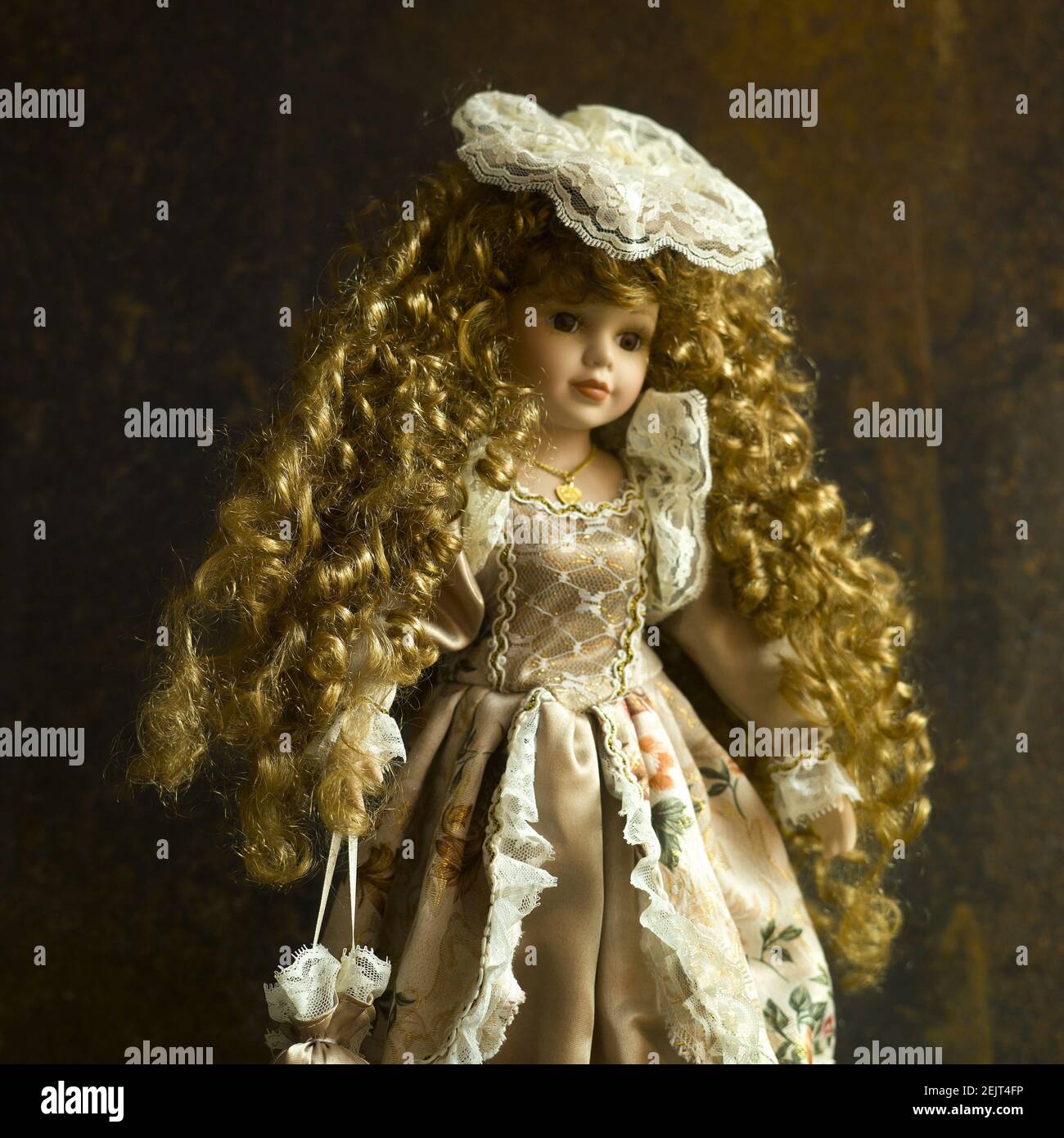 Vintage Puppe mit einem schönen Kleid und goldenen Strähnen auf Der braune Hintergrund Stockfoto