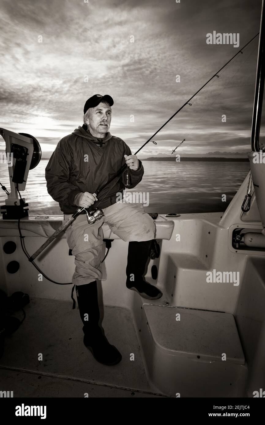 WA20087-00BW..... WASHINGTON - Phil Russell nimmt einen Moment zum Entspannen, während Tintenfisch Angeln auf dem Puget Sound. Stockfoto