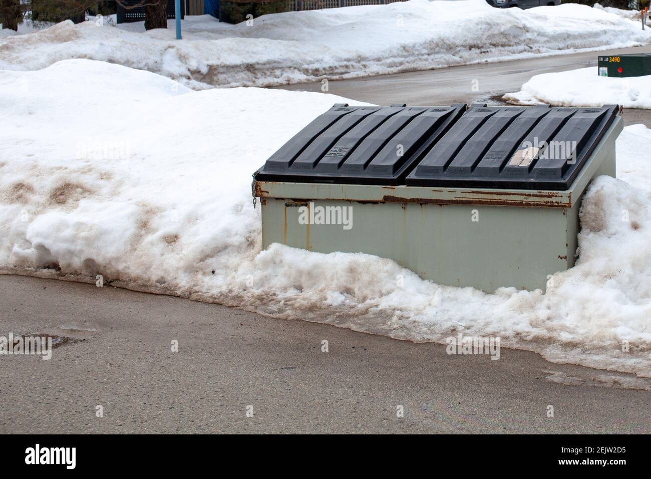 Ein großer Metallmüllbehälter sitzt auf der Seite einer Straße in einer Eigentumswohnung Korporation für die Bewohner, um ihren Müll zu entsorgen. Der Behälter ist alt und rostig, und Stockfoto
