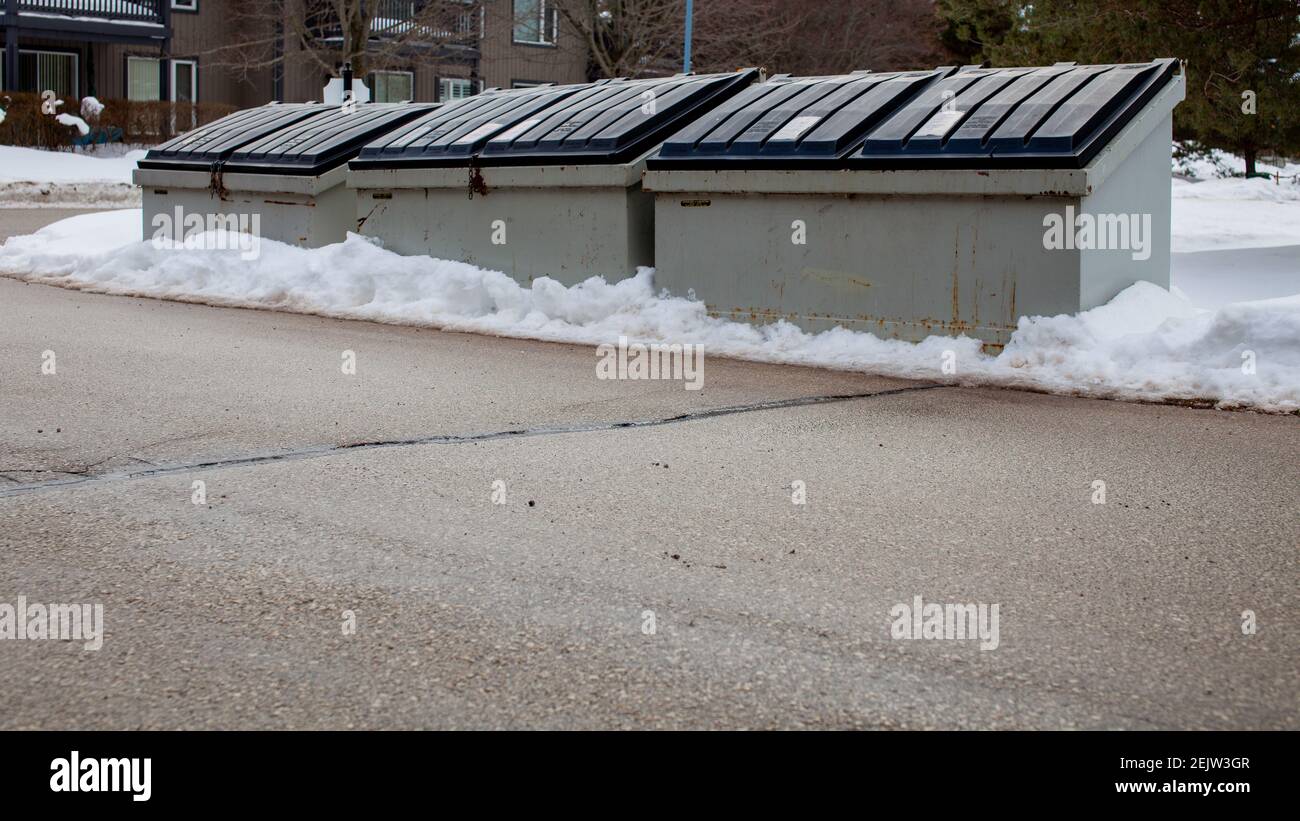 Drei große Metallmüllbehälter sitzt auf der Seite einer Straße in einer Eigentumswohnung Corporation für die Bewohner, um ihren Müll zu entsorgen. Der Behälter ist alt und rostig, Stockfoto