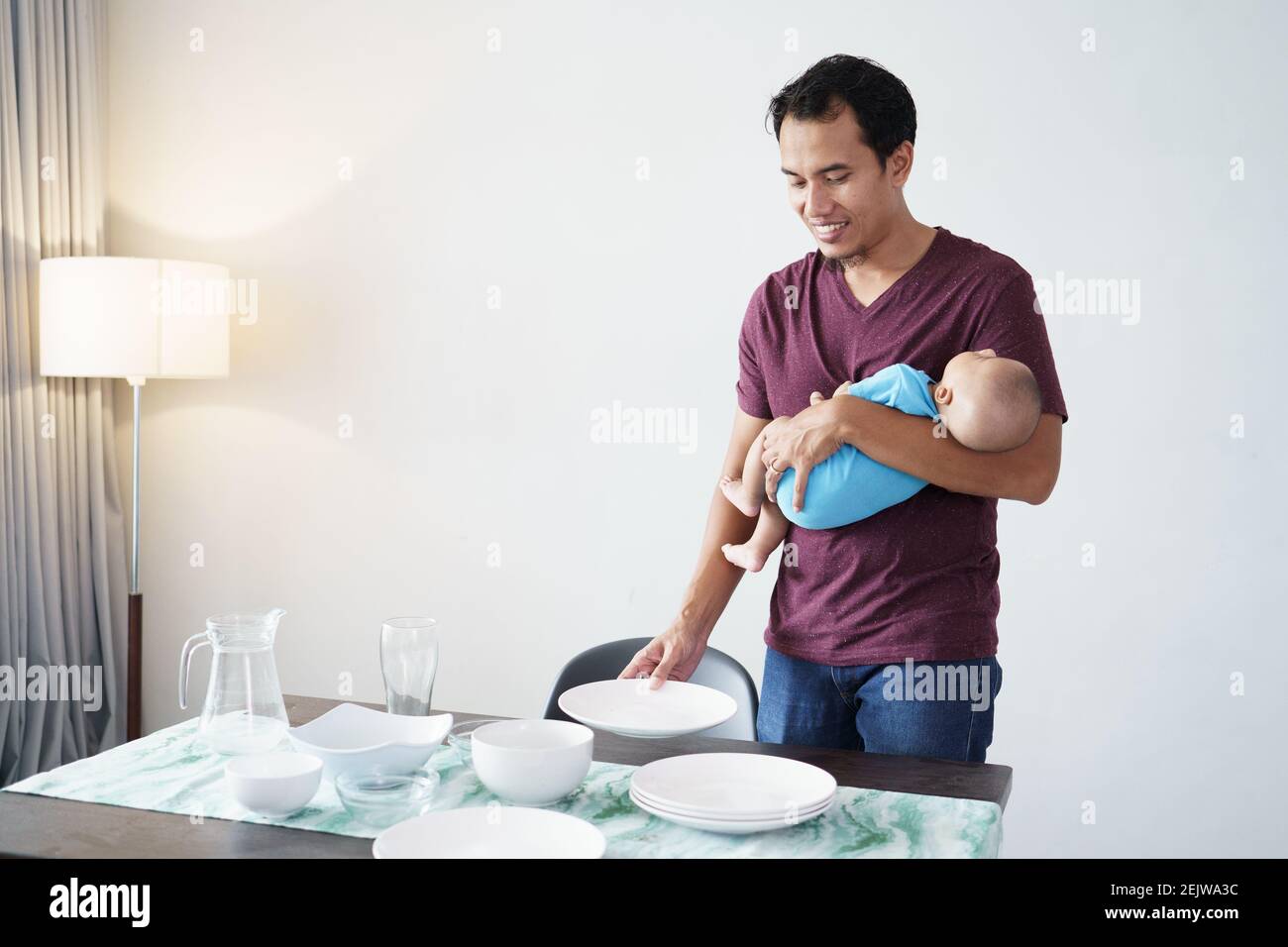 Porträt eines alleinerziehenden Vaters, der zu Hause beim Tragen Aufgaben erledigt Sein Baby Stockfoto