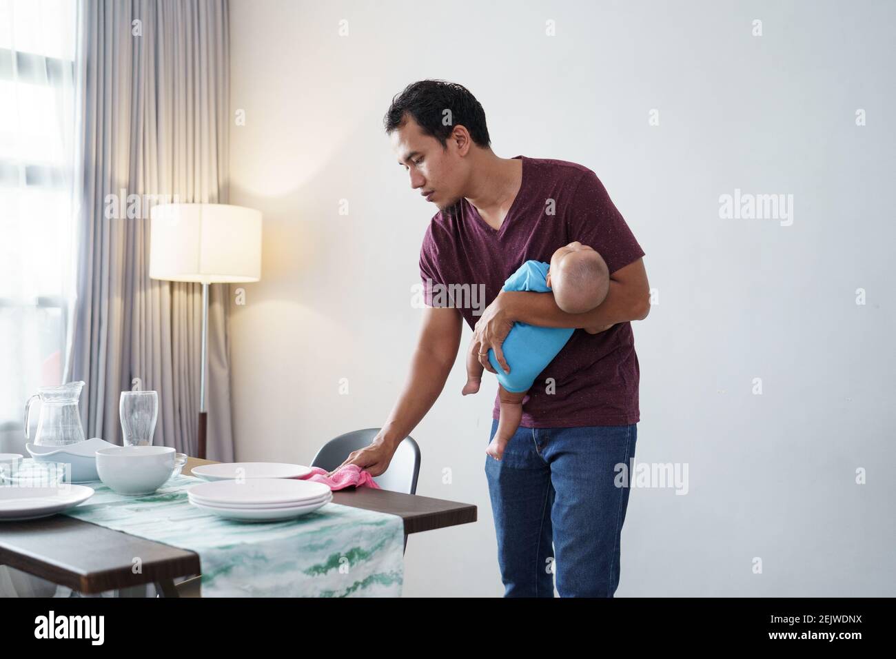 Porträt eines alleinerziehenden Vaters, der zu Hause beim Tragen Aufgaben erledigt Sein Baby Stockfoto