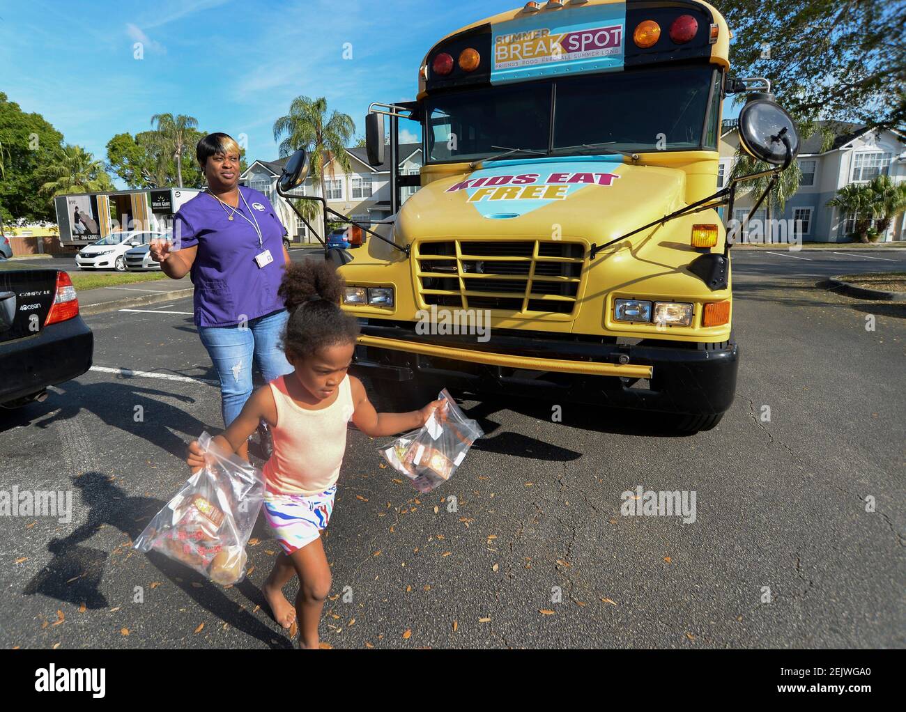 16. März 2020; Vero Beach, FL, USA; Khawndice Colley (links) mit dem School District des Indian River County Mobile Cafe wacht über Aylonie Wiggins, 4, als sie auf ihrem Heimweg in der Nachbarschaft von Pemberly Palms die Straße überquert, nachdem sie am Montag, 16. März 2020, im Indian River County ein kostenloses Frühstück vom Mobile Cafe erhalten hat. Am Freitag ordnete das staatliche Bildungsministerium die Schließung aller öffentlichen Schulen bis März 27th an, um die Ausbreitung des Coronavirus im ganzen Staat zu stoppen. Die mobilen Cafés des SDIRC bieten Kindern während des gesamten Tages kostenloses Frühstück und Mittagessen für Kinder bis 18 Jahre Stockfoto