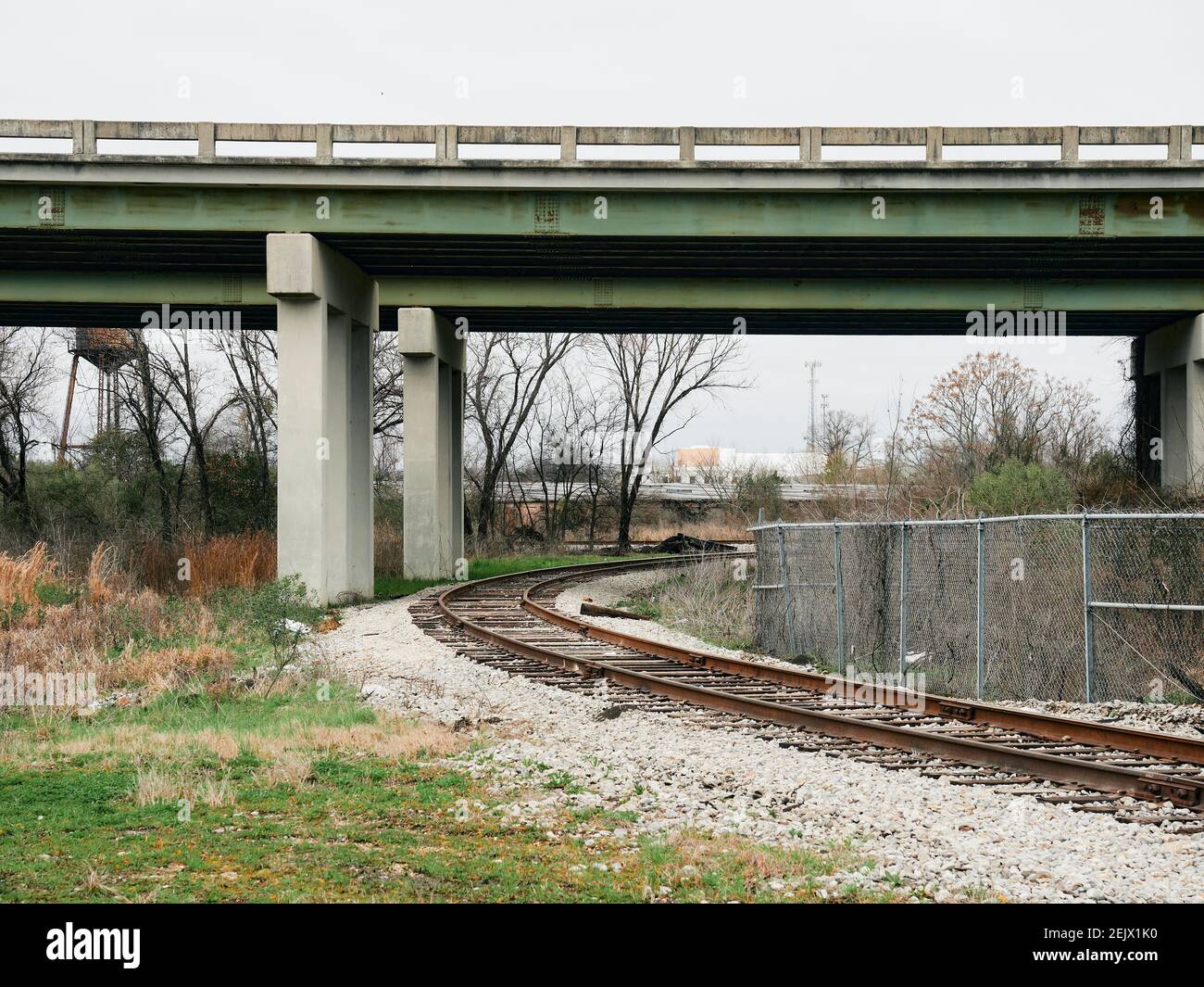 Eingleisige Eisenbahnspur kurvig oder Kurve unter einer Autobahnbrücke in Montgomery Alabama, USA. Stockfoto