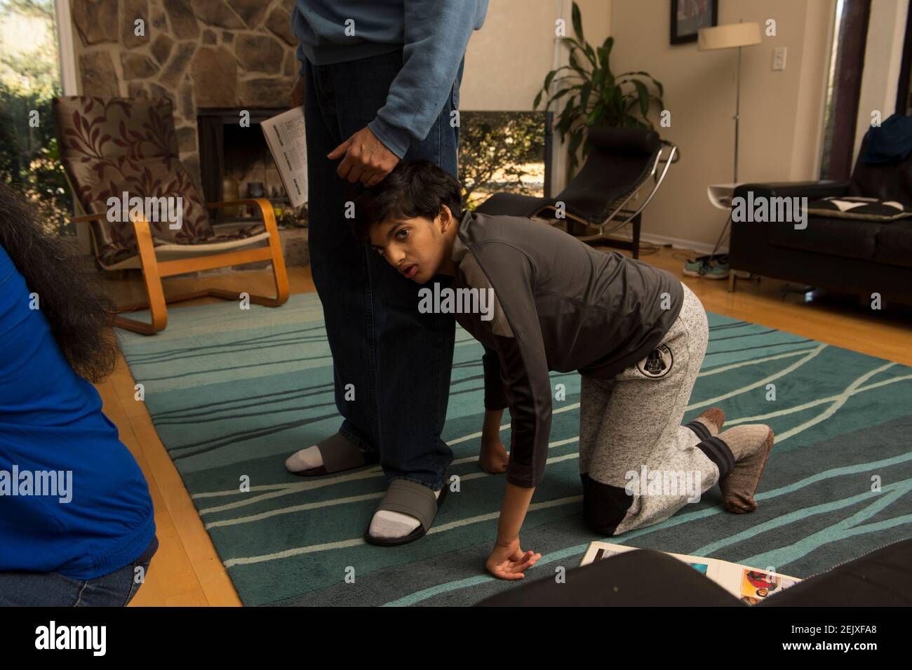 Marietta, GA, USA. Februar 2021, 22nd. Inesh Nayak kriecht GaneshÃs Wohnzimmer familyÃs seines Vaters zur Seite. Inesh, 19, ist meist nonverbal und aufgrund tiefgreifender Entwicklungsherausforderungen nicht in der Lage zu gehen, kann aber auf Händen und Knien in ihrem einstöckigen Zuhause herumlaufen. Bei ihm wurden Trisomie 9 und das CRI du Chat-Syndrom diagnostiziert, beides genetische Chromosomenstörungen. Sitara und ihr Mann Ganesh konnten ihren Sohn zu Hause mit Hilfe von in-Home-Unterstützungen versorgen, die durch das stateÃs Medicaid-Programm finanziert werden, aber die jüngsten Budgetkürzungen könnten die Inesh zwingen, in eine Gruppe hom verlegt zu werden Stockfoto