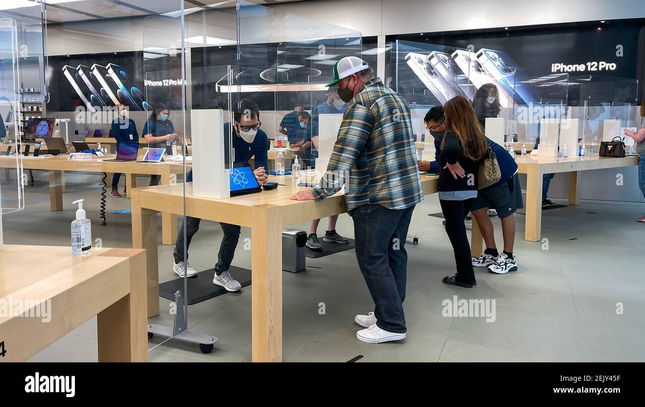 Orlando, FL USA - 5. Februar 2021: Apple-Mitarbeiter warten auf Kunden mit Plexiglas-Schilden zwischen der Woche mit Gesichtsmasken wegen der Coronavi Stockfoto