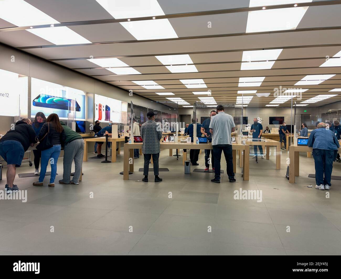 Orlando, FL USA - 5. Februar 2021: Apple-Mitarbeiter warten auf Kunden mit Plexiglas-Schilden zwischen der Woche mit Gesichtsmasken wegen der Coronavi Stockfoto